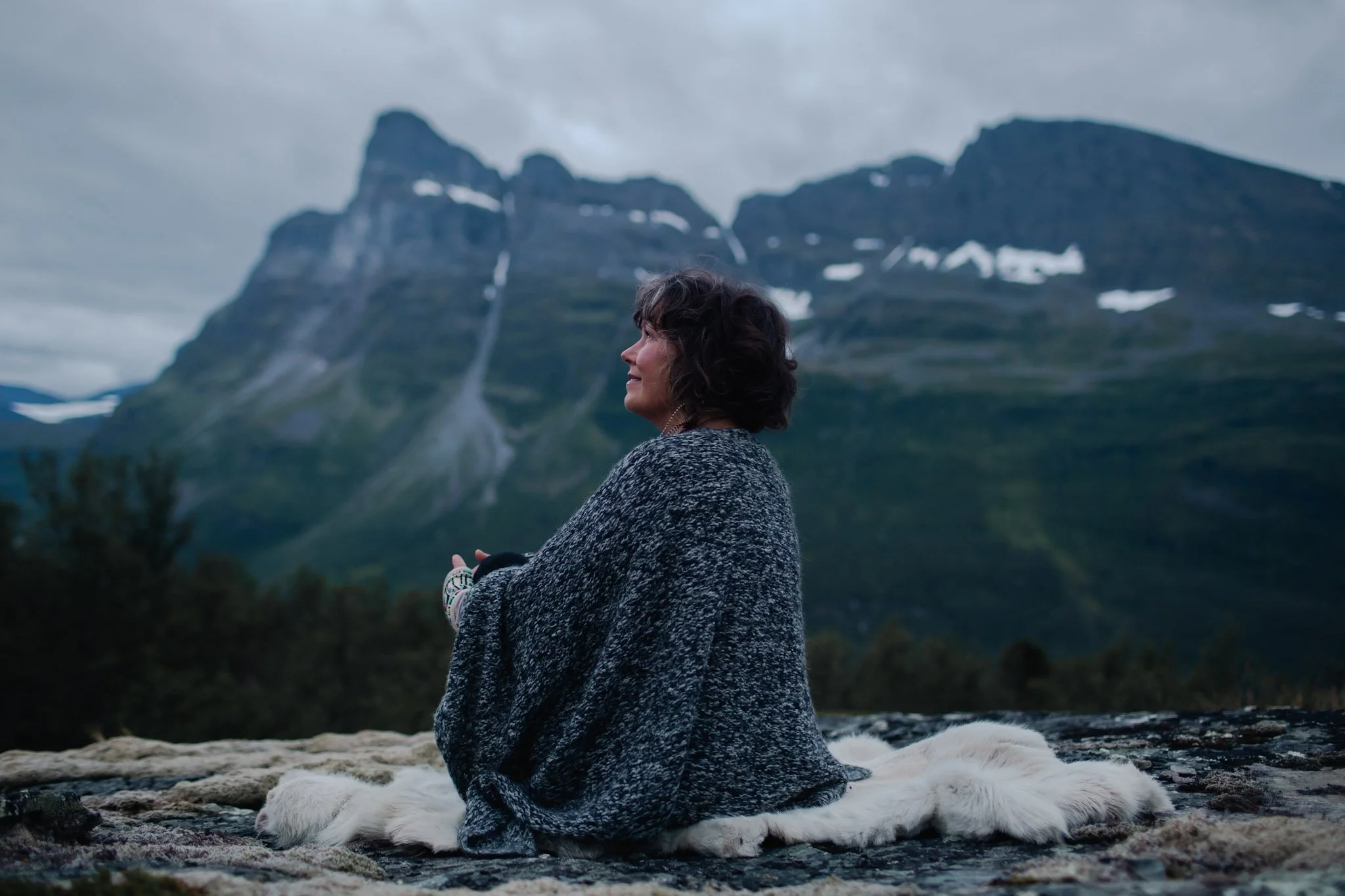 Chloë Rain in Signaldalen Valley sitting on a reindeer skin smiling