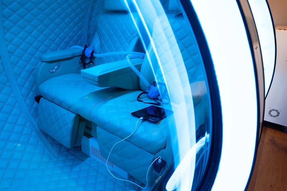 View inside a HBOT chamber at CryoClinic, surrounded by blue lights, in a wellness facility.