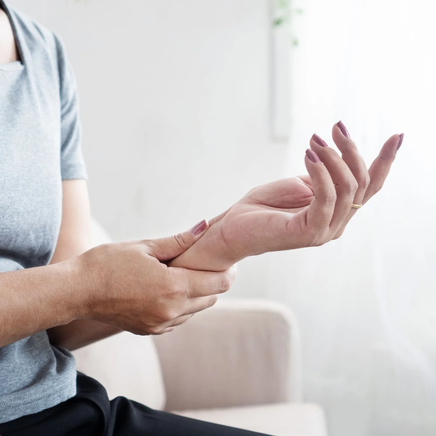 Young woman with curly hair looks at her reflection in a mirror, feeling worried or stressed, with her hand on her forehead.
