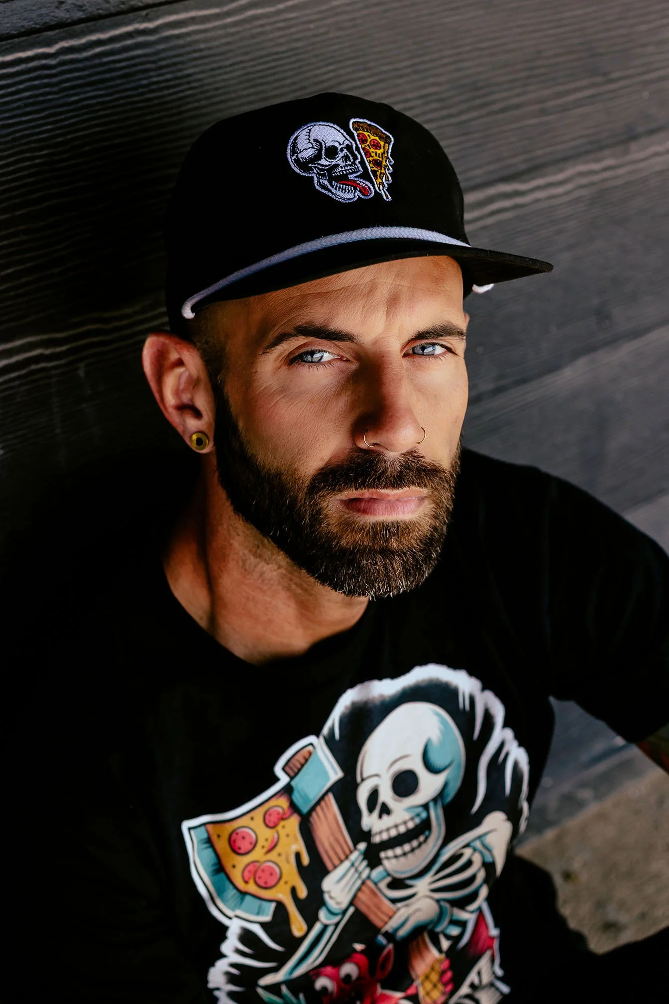 Close-up apparel photography of Skeleton Pizza Supply Co graphic t-shirt and hat