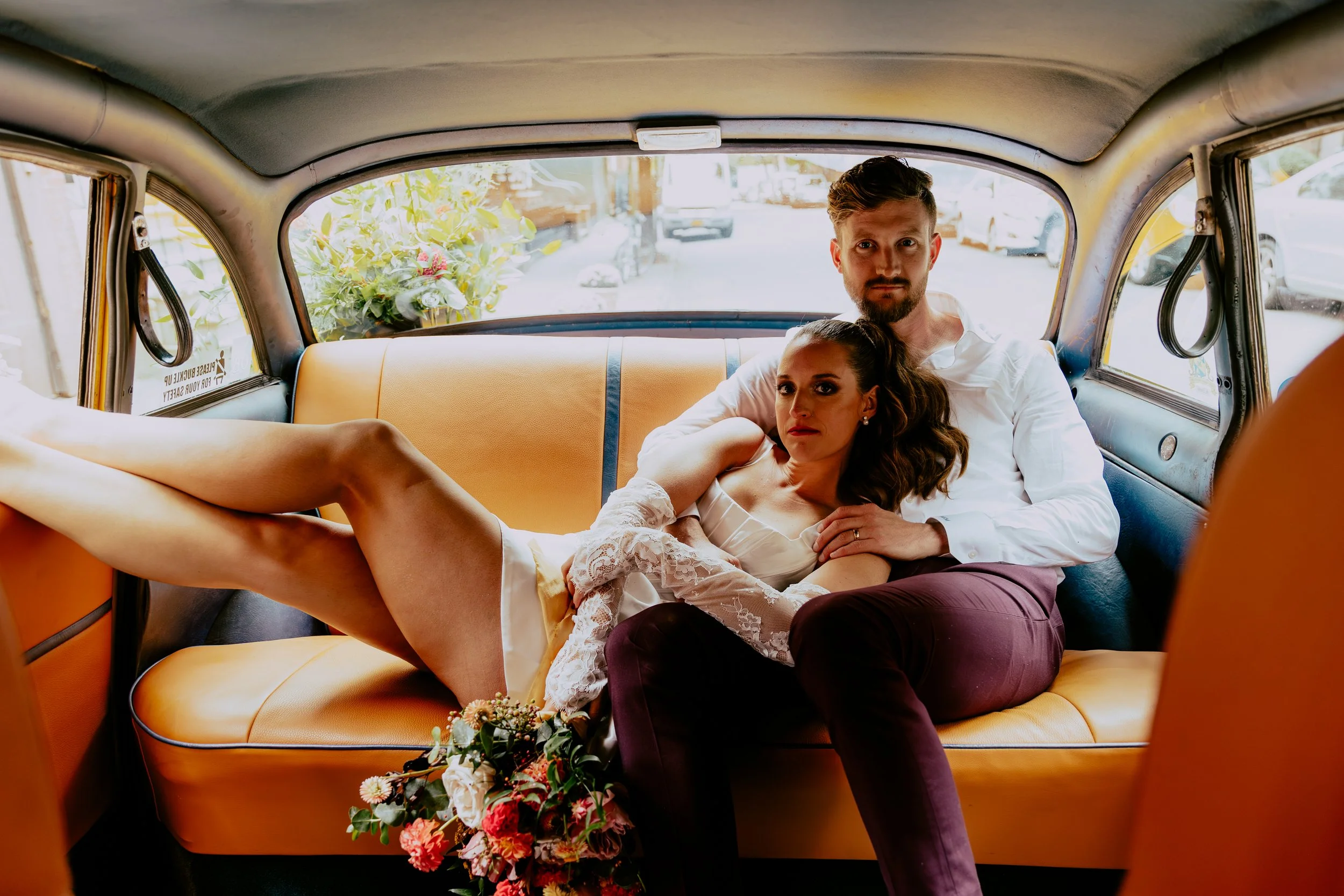 couple being cozy in taxi cab after their elopement