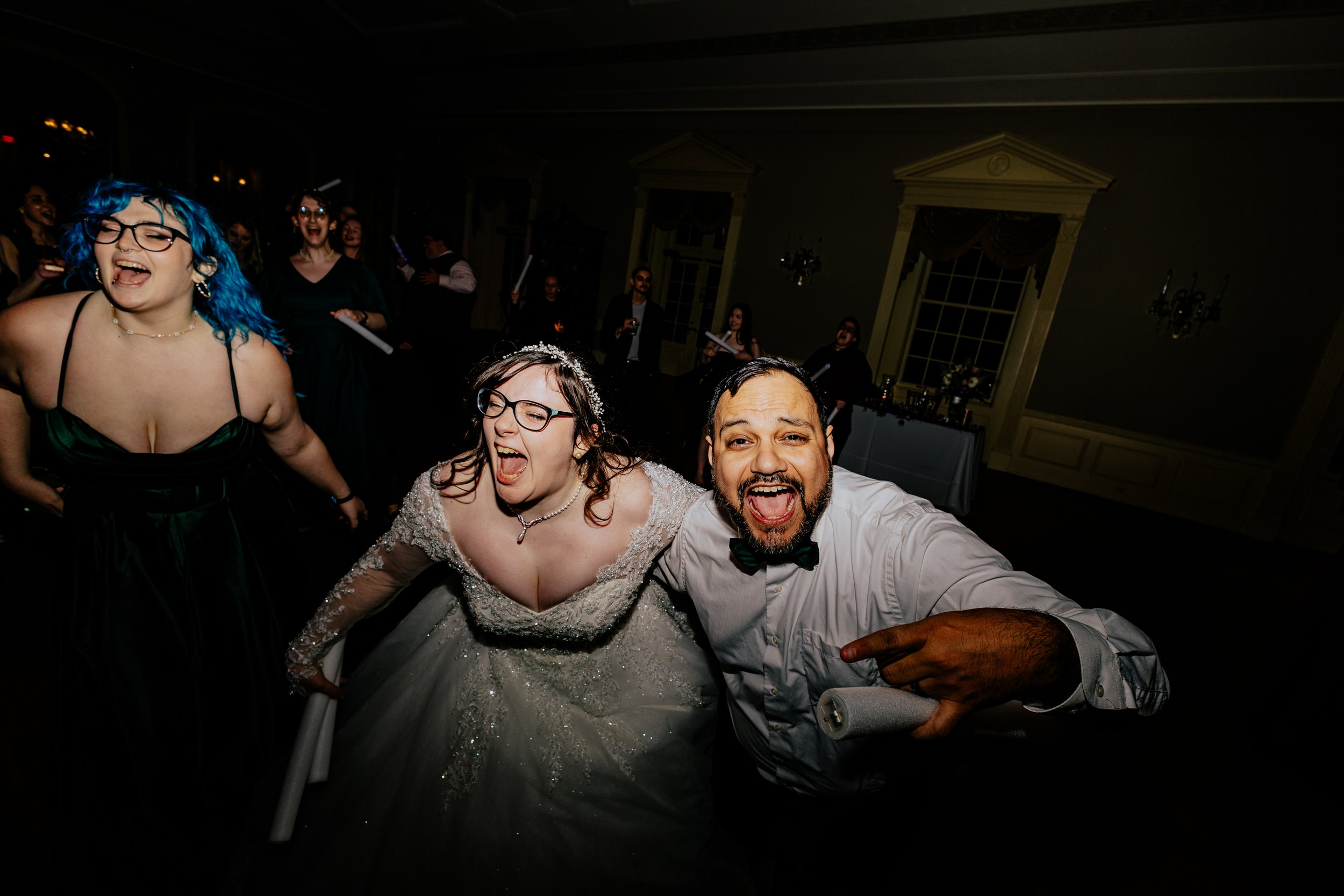 Newlywed couple laughing and celebrating on the dance floor during a lively wedding reception with friends and family.