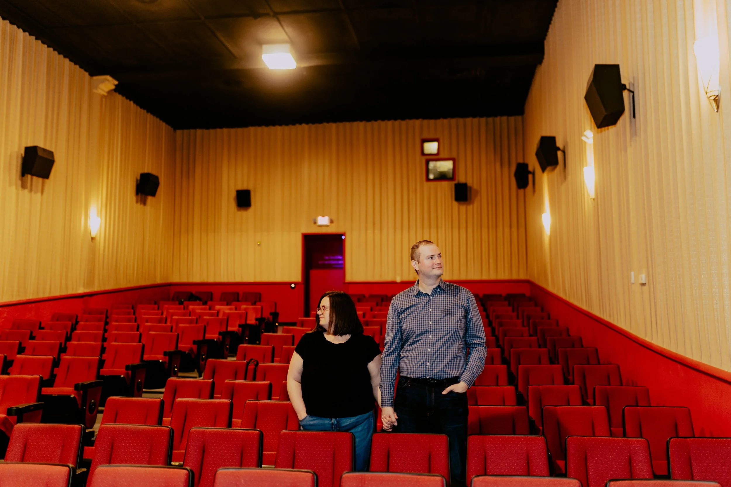 Detroit engagement photographer capturing a couple holding hands inside a historic movie theater during their engagement session.