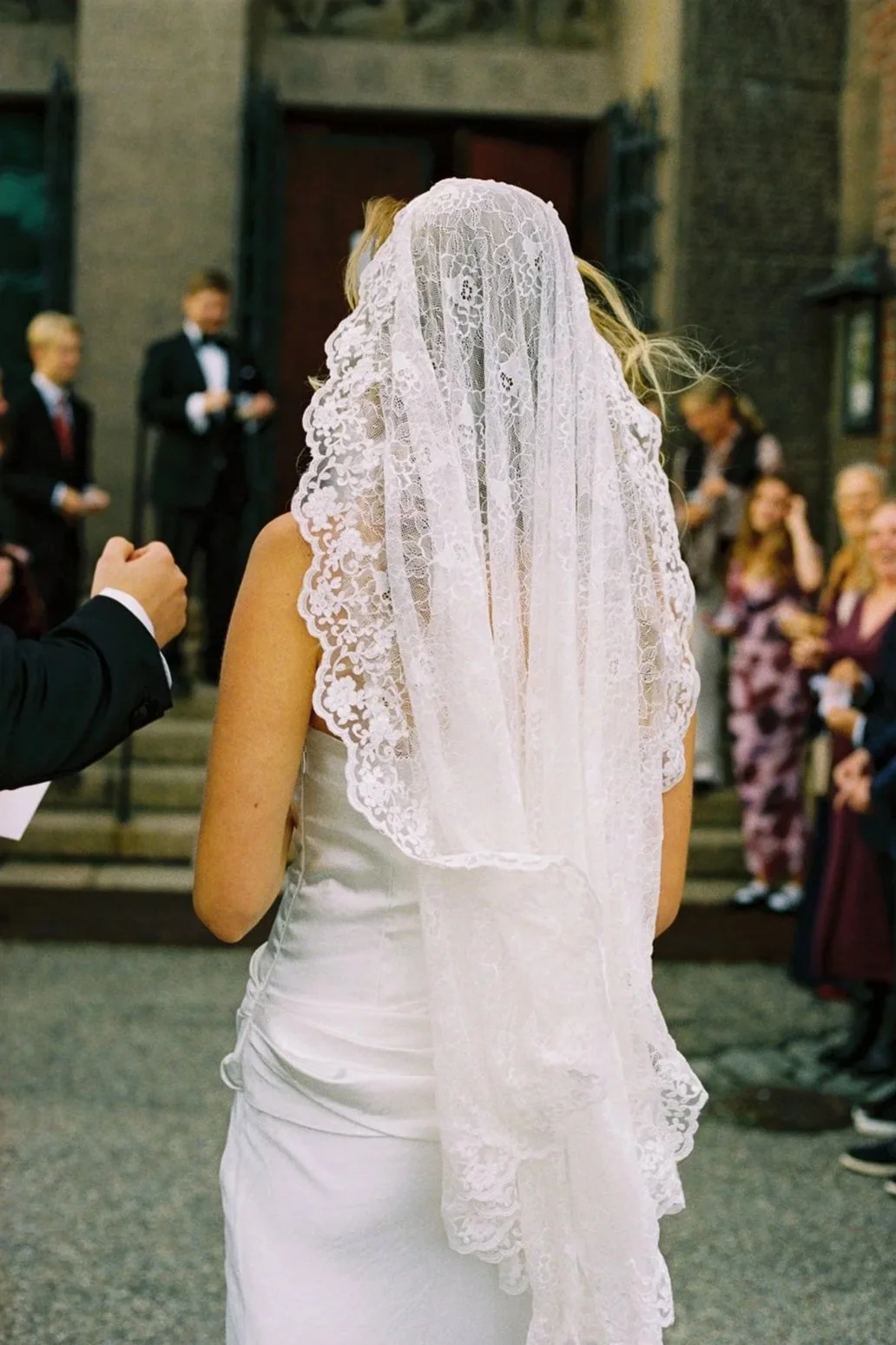 Photograph from the back of Bride in veil facing her guest