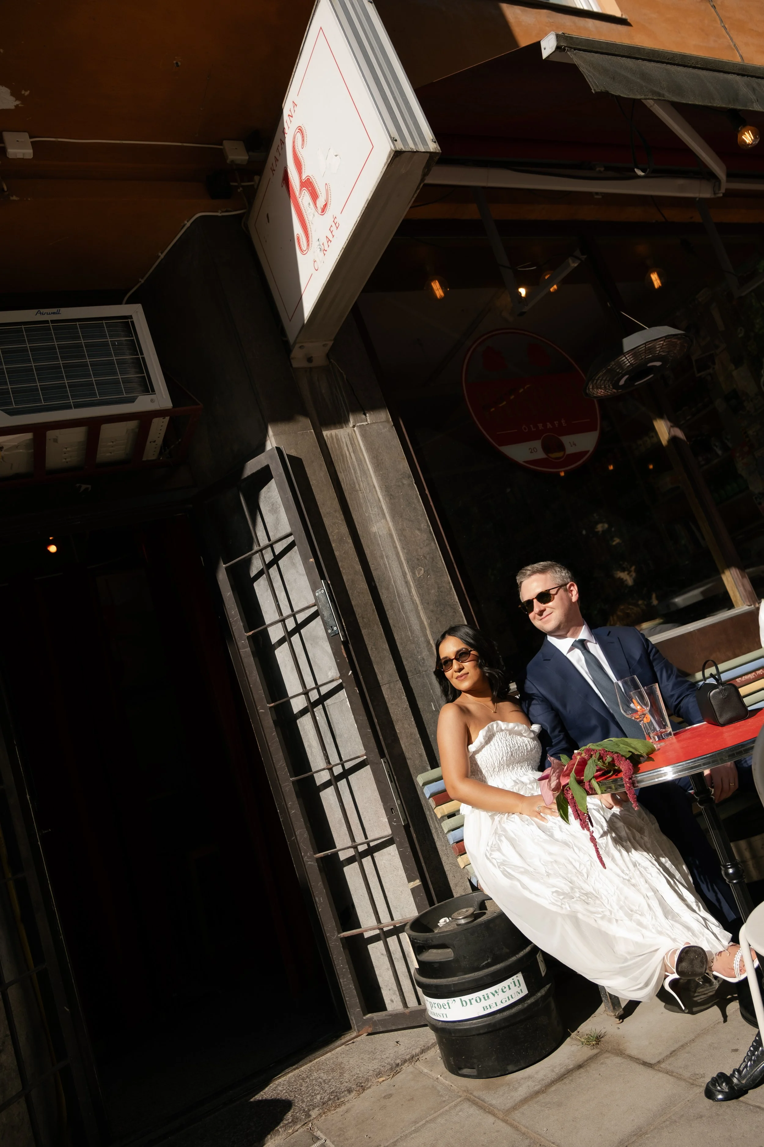Couple in wedding dress and suit enjoying a drink after their city elopement in Stockholm