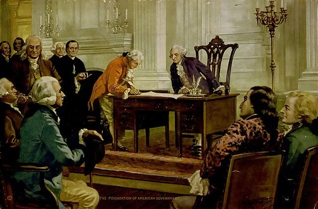 Historical painting of the signing of the Declaration of Independence with men in 18th-century attire gathered around a table in a formal room.