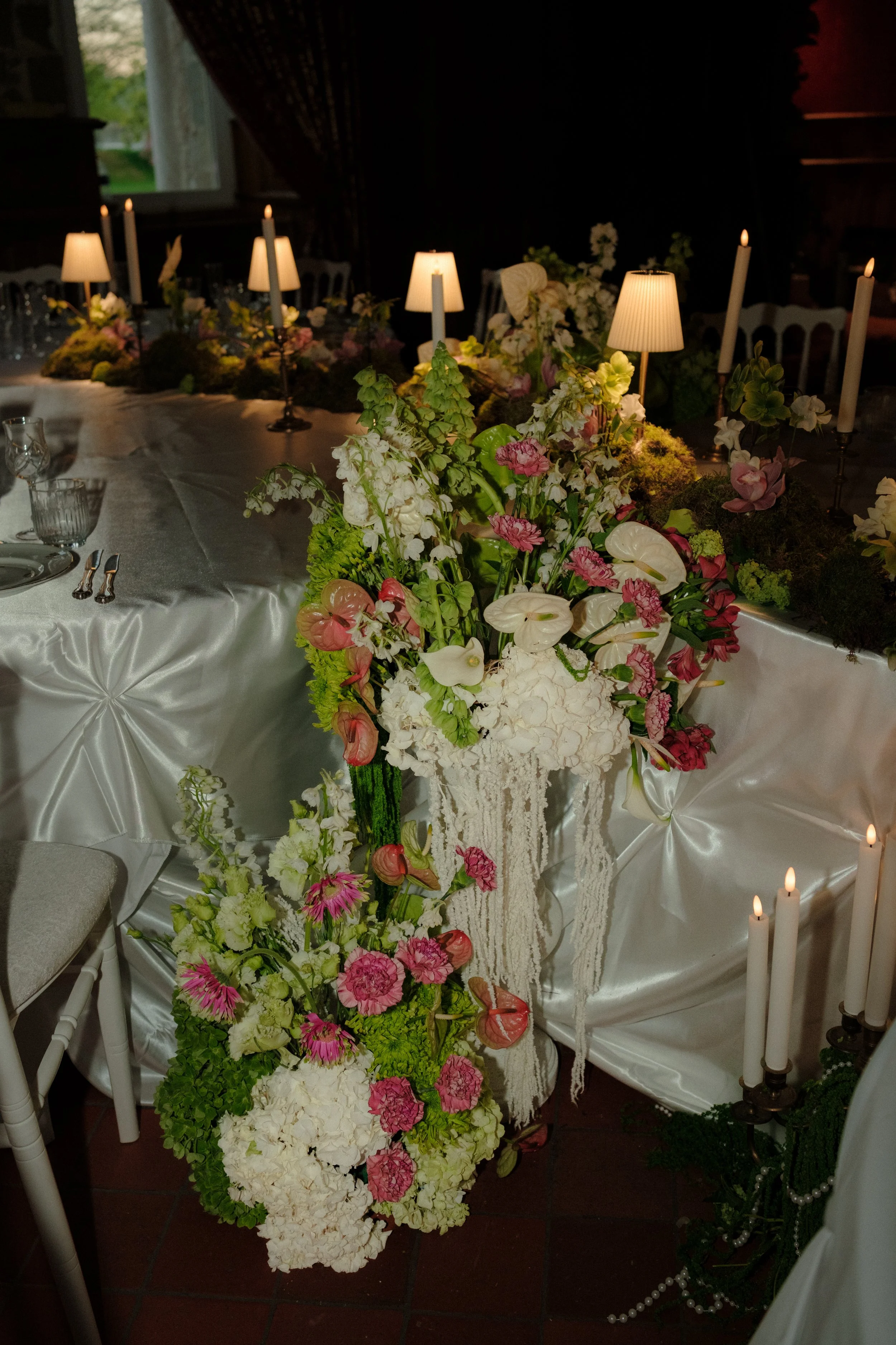 Une grande table décorée avec des fleurs colorées et des bougies, dans une ambiance chaleureuse et élégante pour un événement spécial.