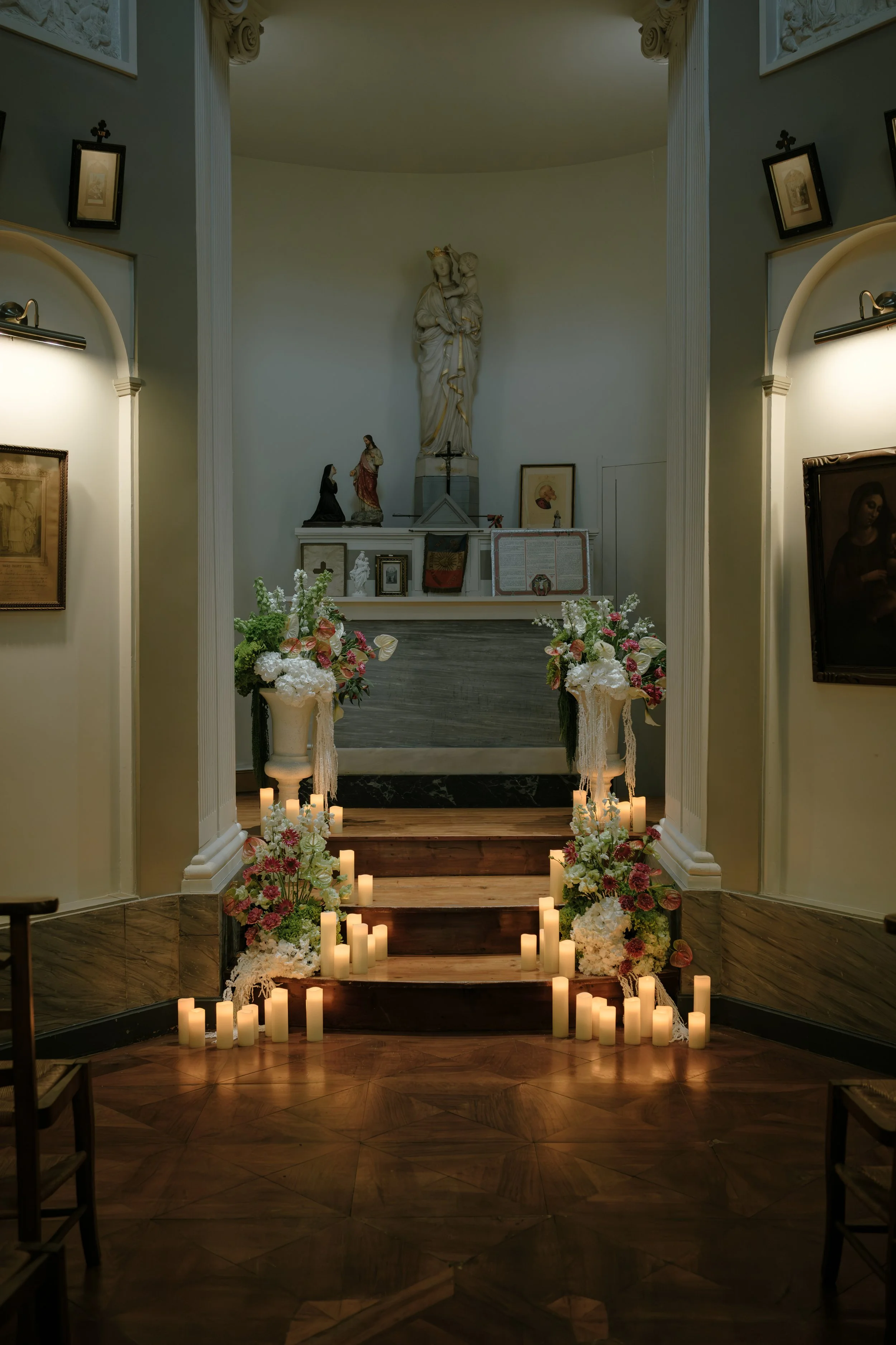 Intérieur d'une chapelle avec statues religieuses, fleurs et bougies pour une cérémonie ou un rituel religieux.