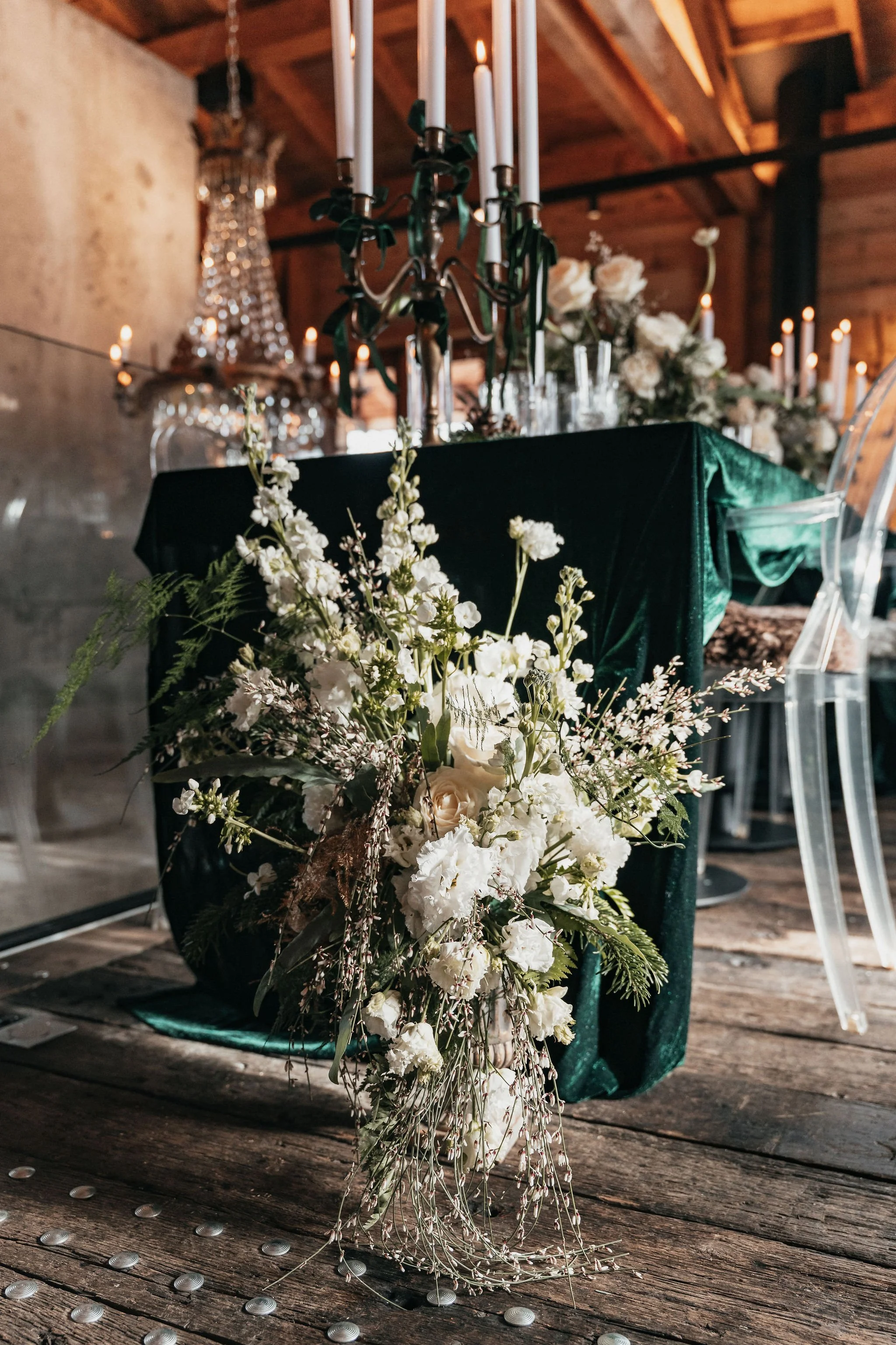 Décoration de table avec un centre de fleurs blanches, chandeliers et chandelles dans un cadre en bois pour un événement ou un mariage.