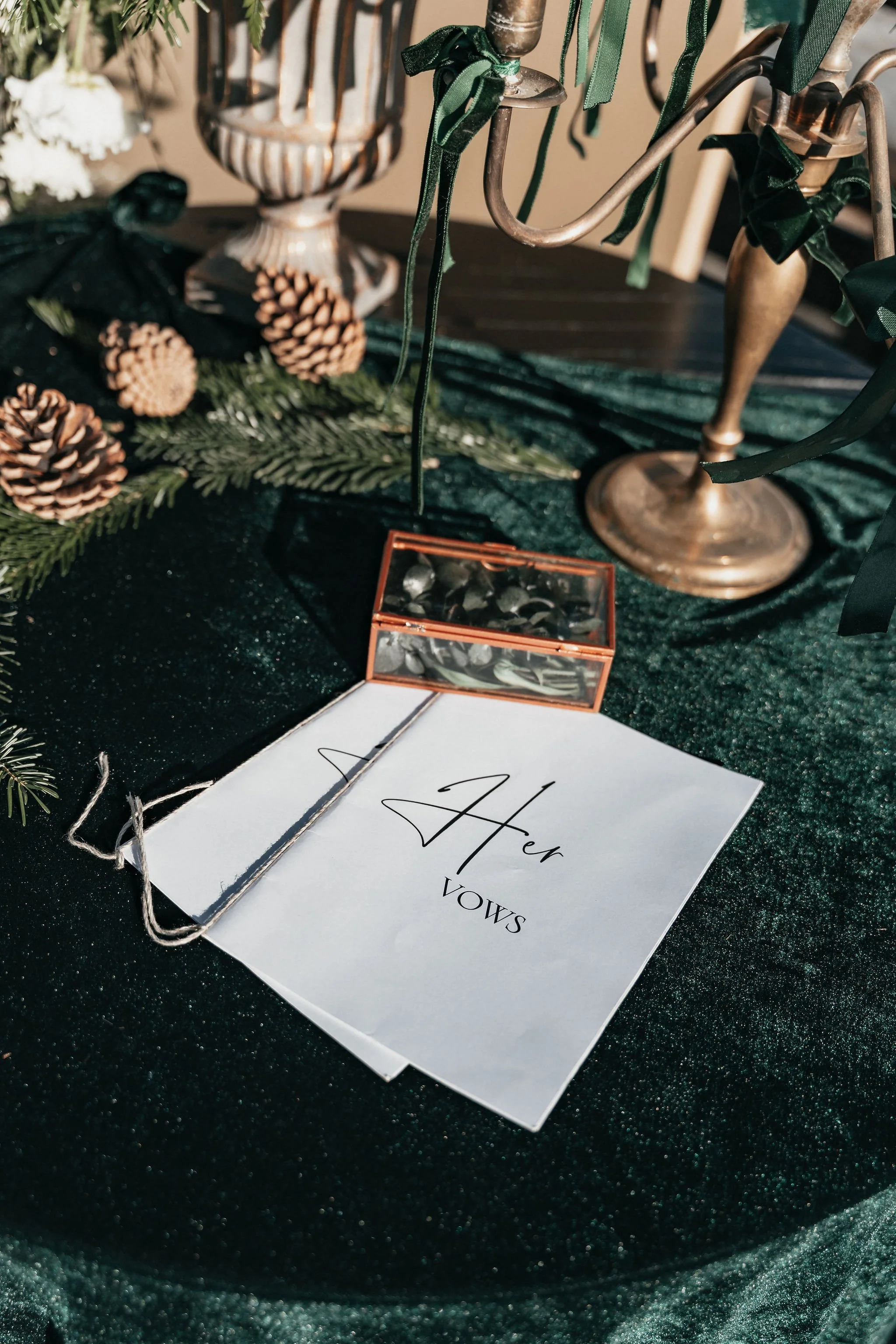 Une table décorée pour un mariage avec une annonce de fiançailles, des sapins, des pommes de pin et un chandelier vintage.