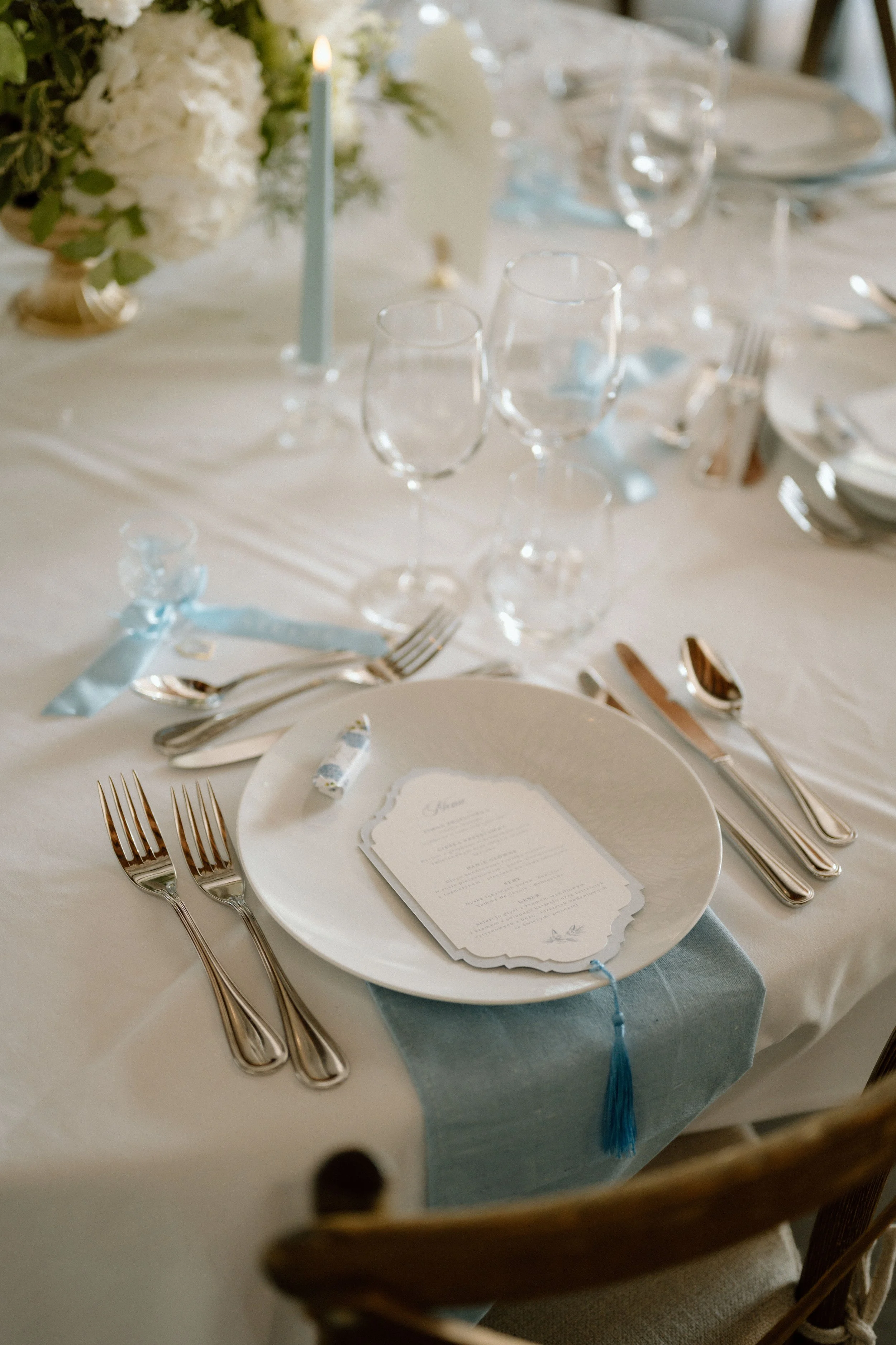 Table de fête élégante avec vaisselle, verres à vin, une bougie et un bouquet de fleurs, décorée pour un événement spécial.