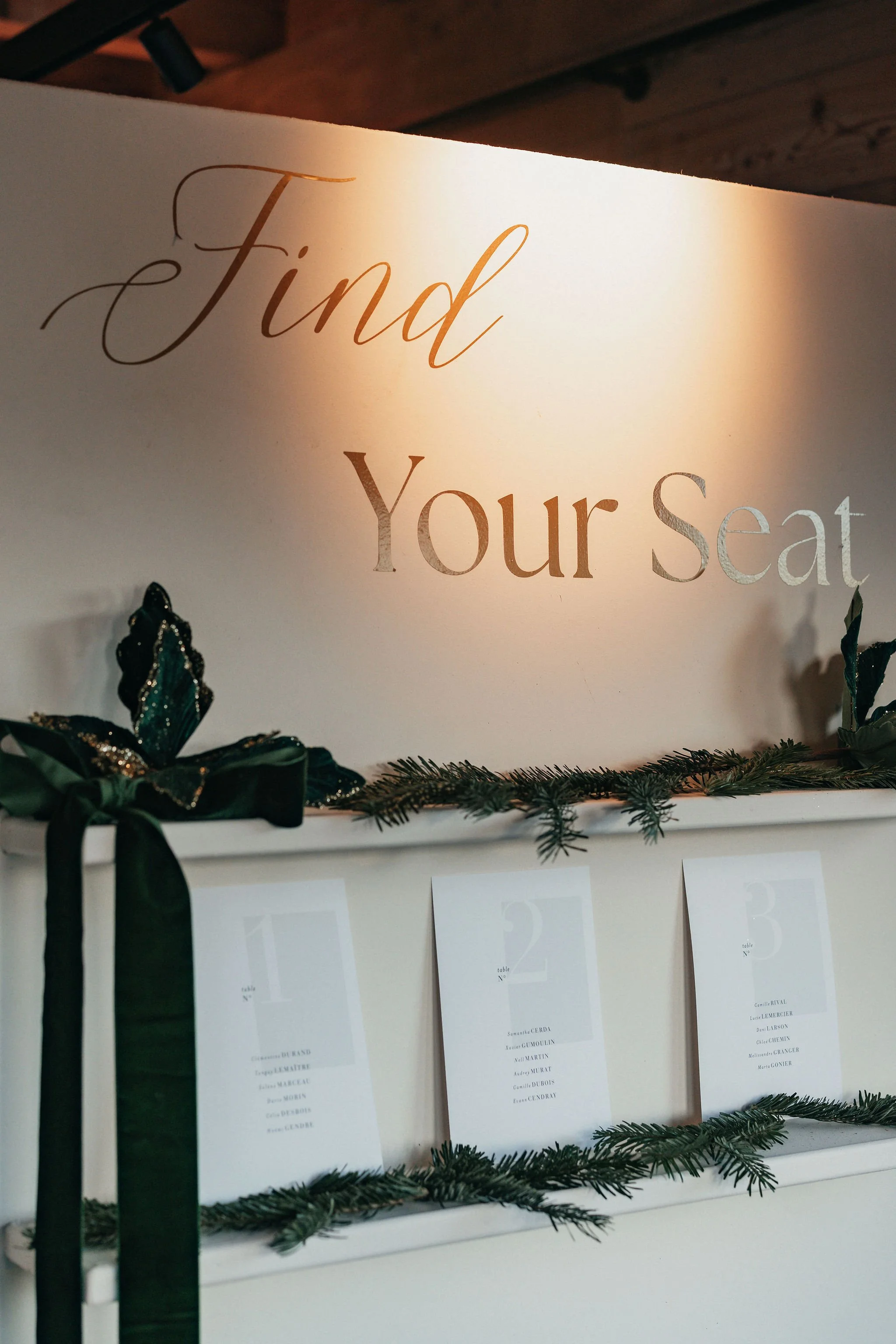 Une signalétique indiquant 'Trouvez votre siège' sur un panneau blanc décoré de guirlandes de sapin