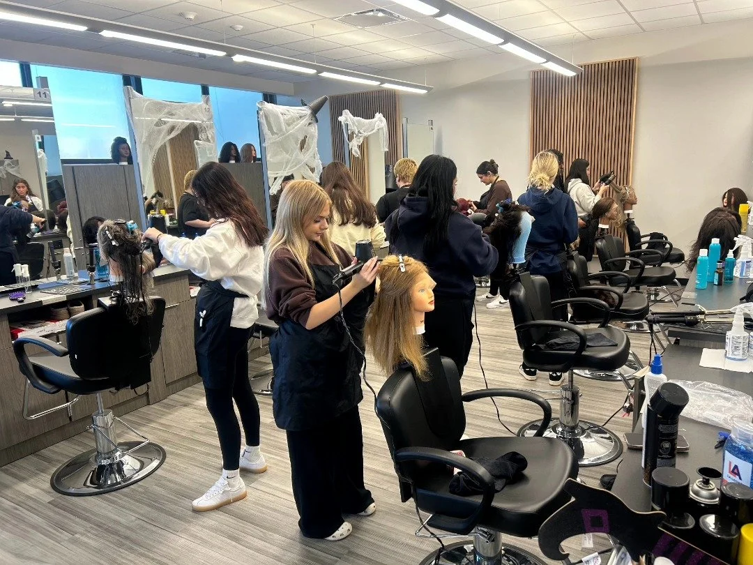 Cosmetology students in the classroom styling wigs for Hair We Share Wig Banks.