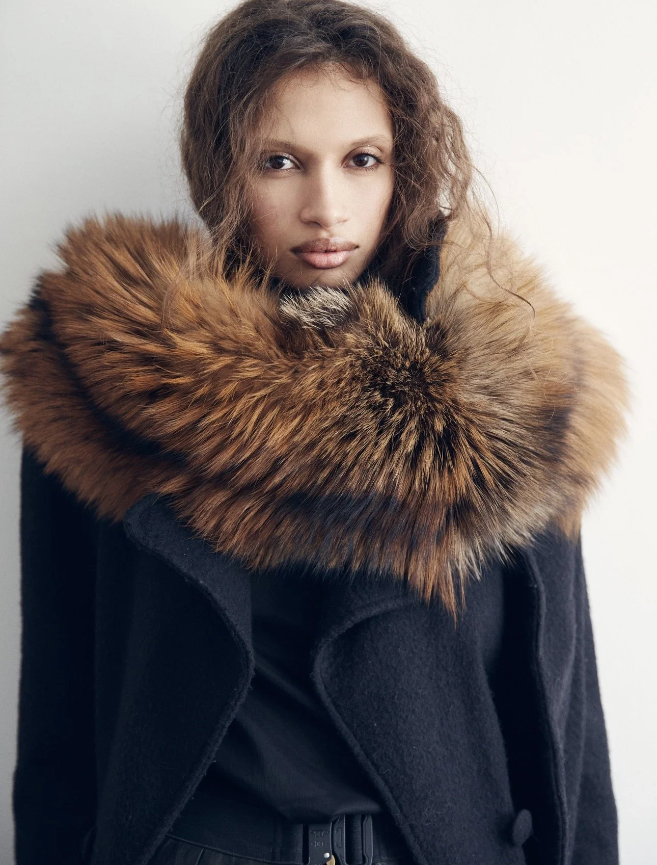A woman wearing a black coat with a large brown fur collar