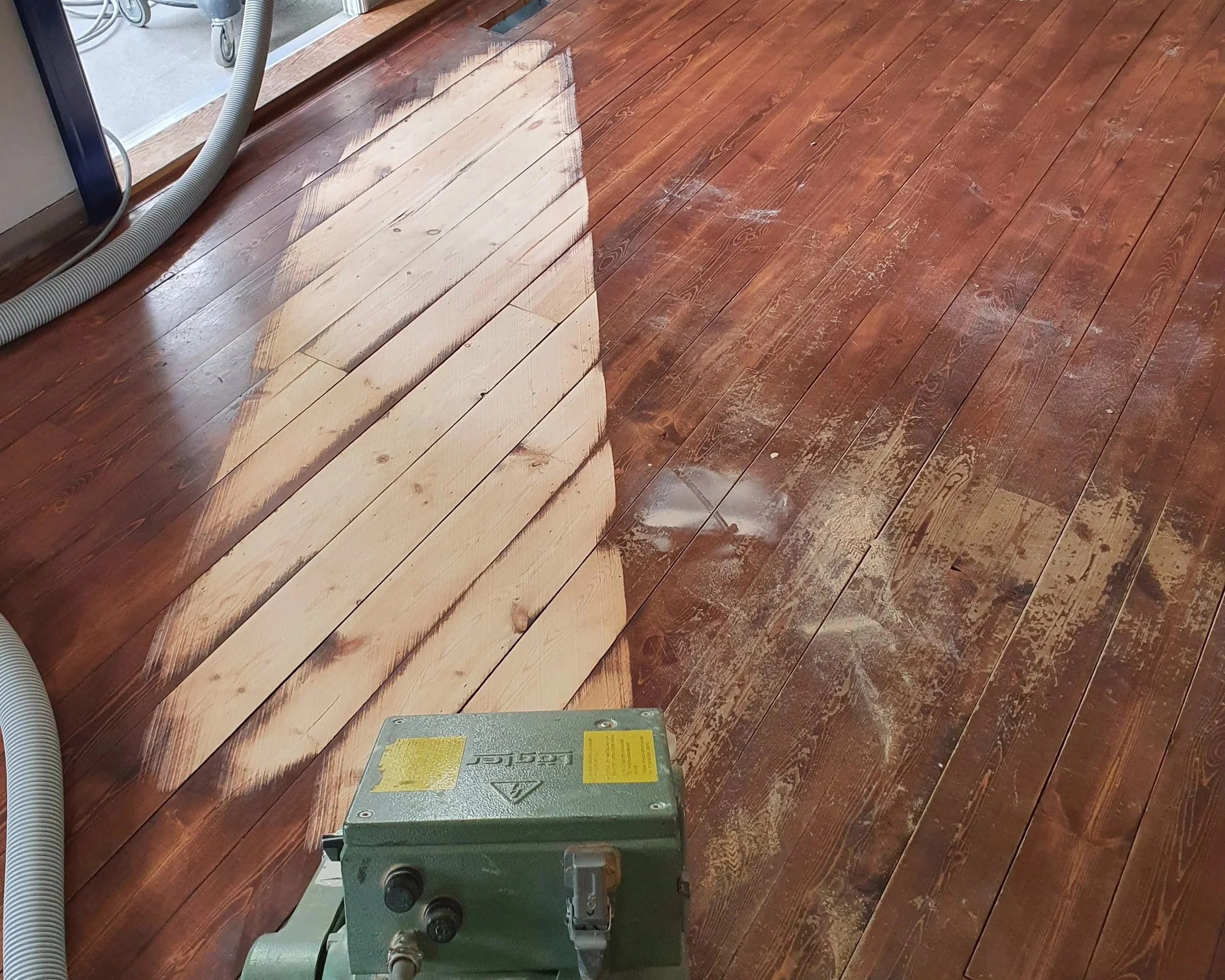 Wooden floor being sanded or refinished with sanding equipment .