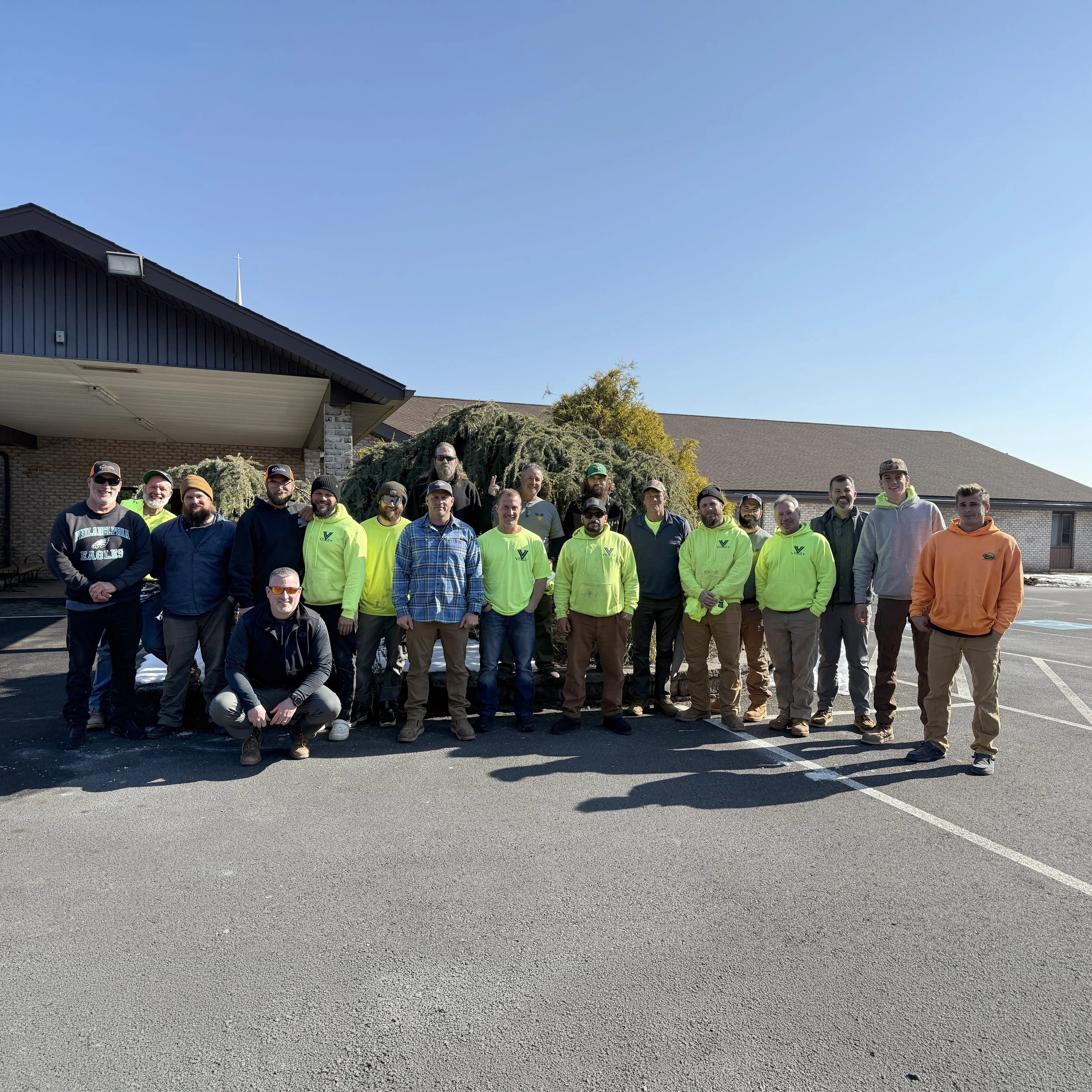 Construction site with seven workers in safety gear on a concrete slab, surrounded by rebar and building materials.