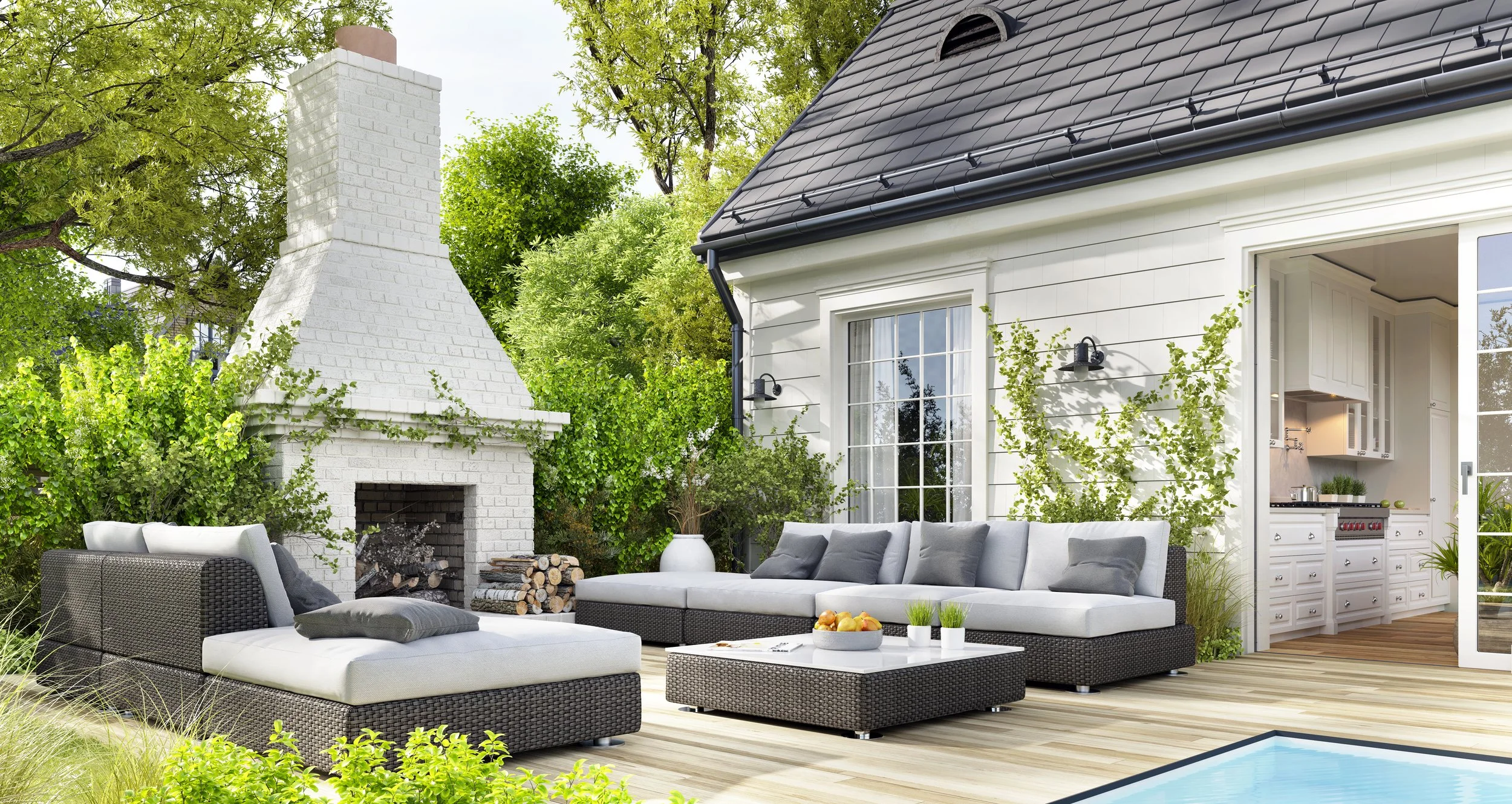 An outdoor patio area with a white brick fireplace, outdoor wicker furniture with gray cushions, greenery, and a sliding glass door leading into a kitchen, with a small pool in the corner.