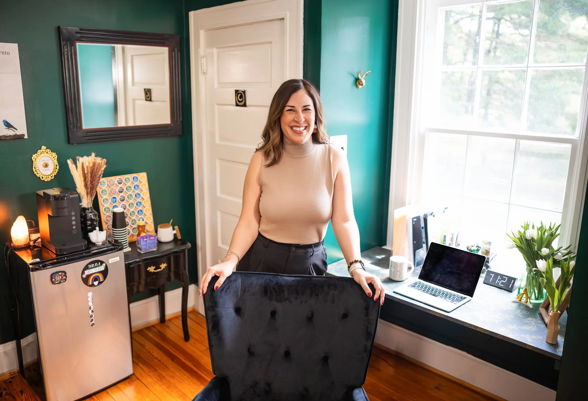 Diana Harden standing behind her office chair in her modern therapy office.