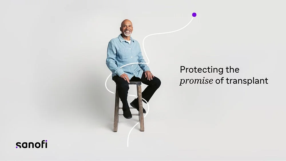 A happy man sat on a stool in a white room, for Sanofi's Transplant campaign