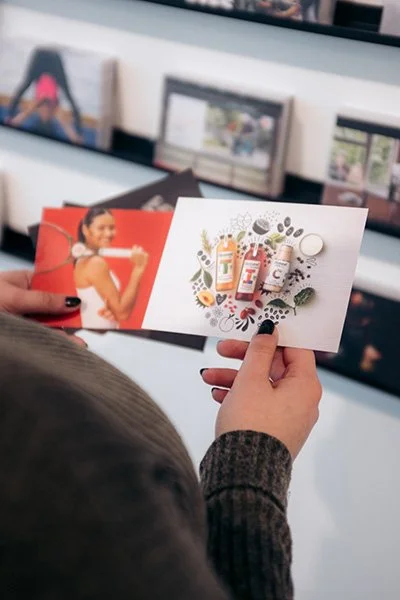 Hands holding two postcards featuring campaigns crated by the agency Hill & Knowlton