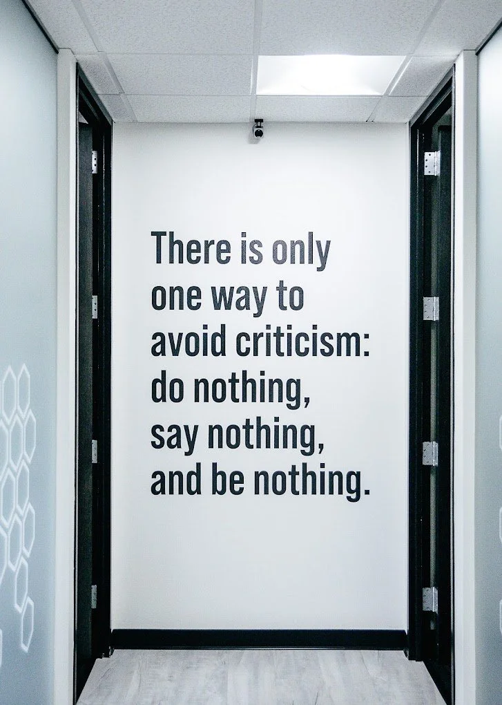 Hallway with motivational quote on wall: 'There is only one way to avoid criticism: do nothing, say nothing, and be nothing.'
