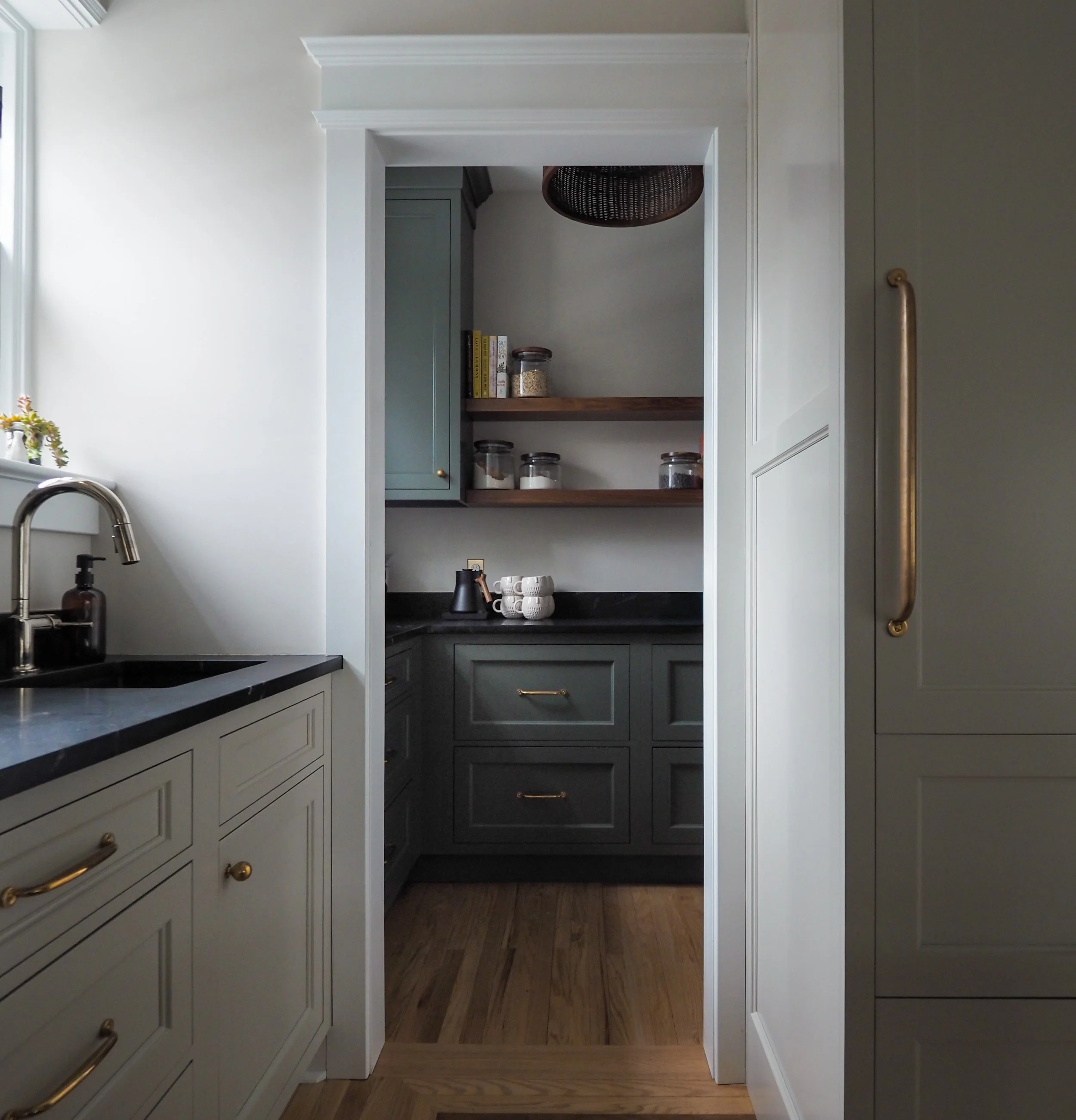 Walk-in pantry with deep green cabinetry, open wood shelving, and black countertops — Studied Milieux kitchen renovation, South Jersey