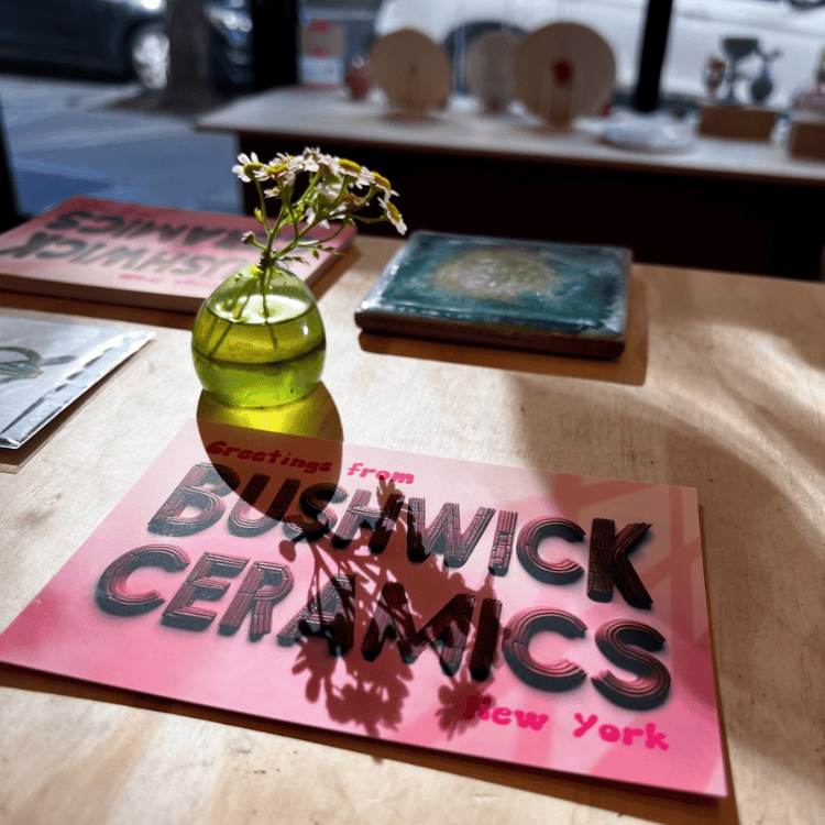 Image of bushwick ceramics logo on a wooden desk as the sun rises into the studio
