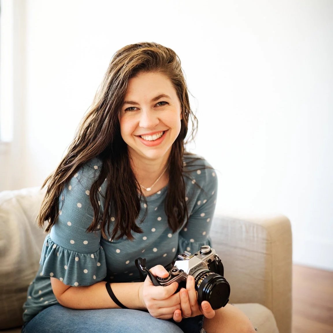 Mandy, newborn and family photographer and owner of Sage & Bloom in Abilene, Texas, smiling and holding her camera.