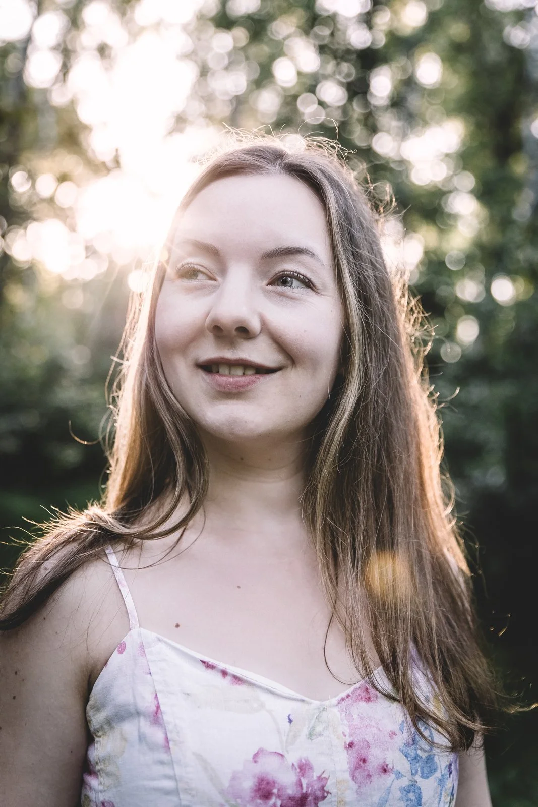 Myriam Trebesius, Ernährungsberaterin für Frauen mit Kinderwunsch, lächelt im weißen Blumenkleid in der warmen Abendsonne