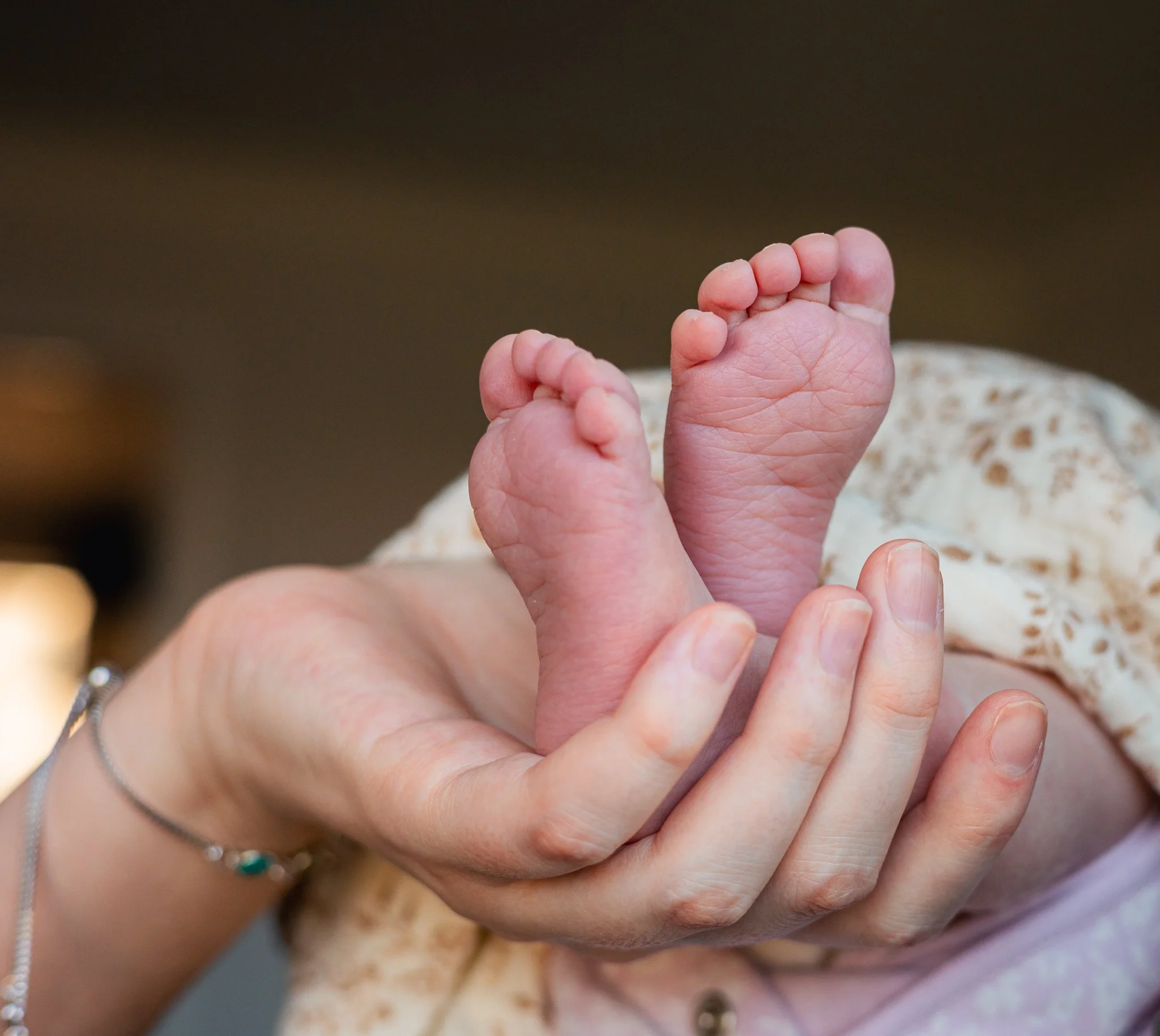 New mum holding newborn feet of daughter