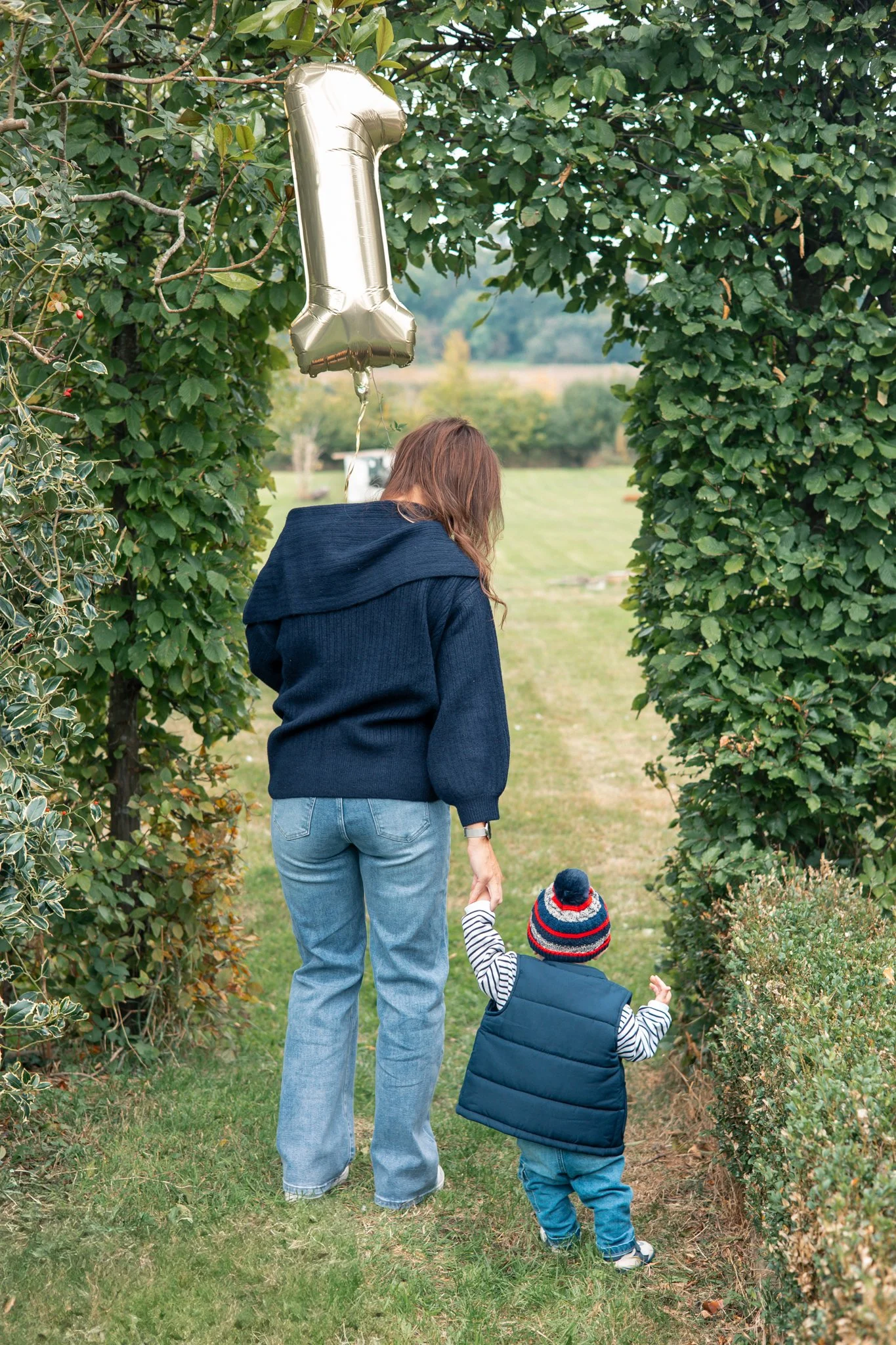 Toddler holding mums hand celebrating first birthday