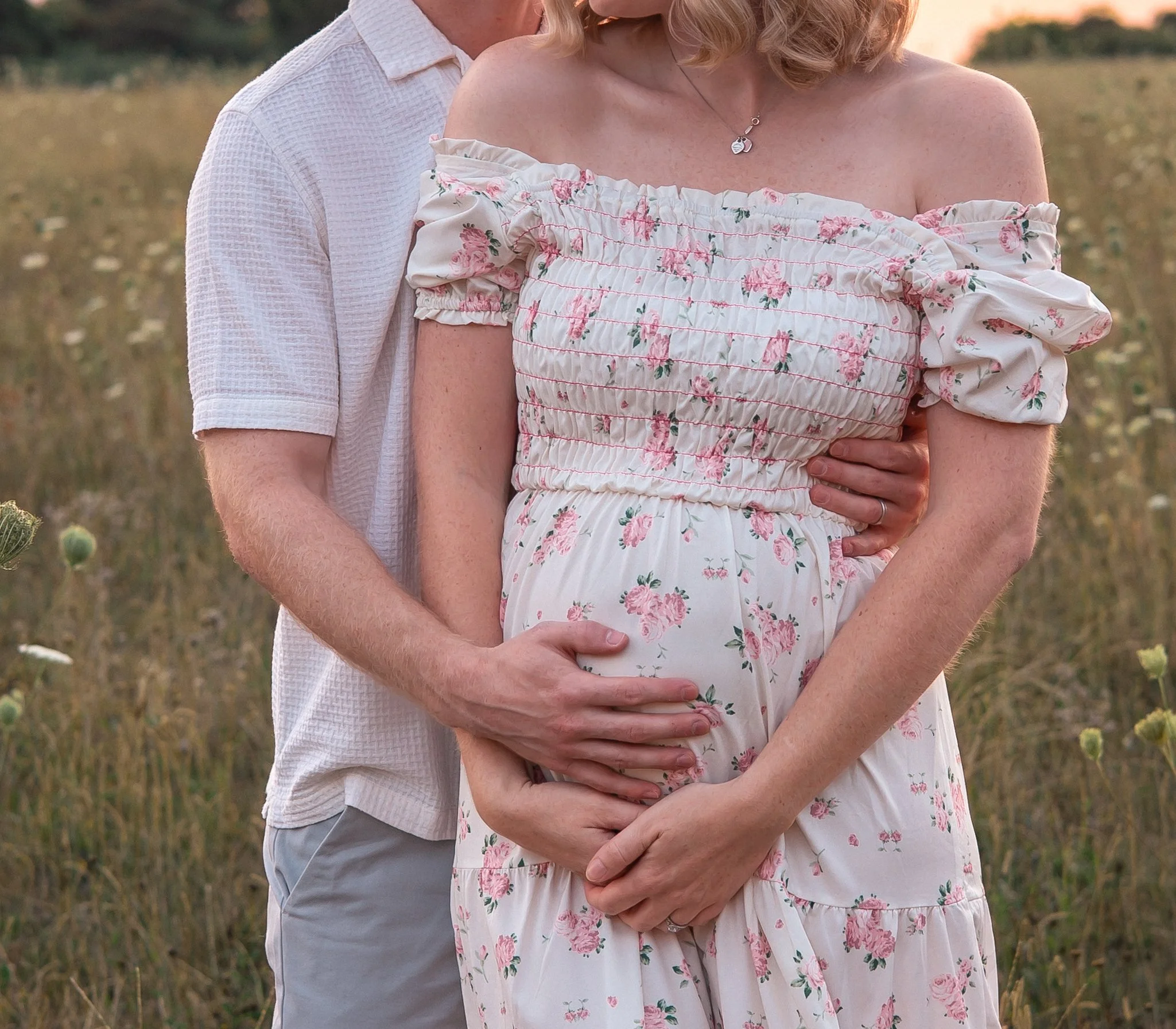 Close up of couple embracing bump in a field in Wiltshire