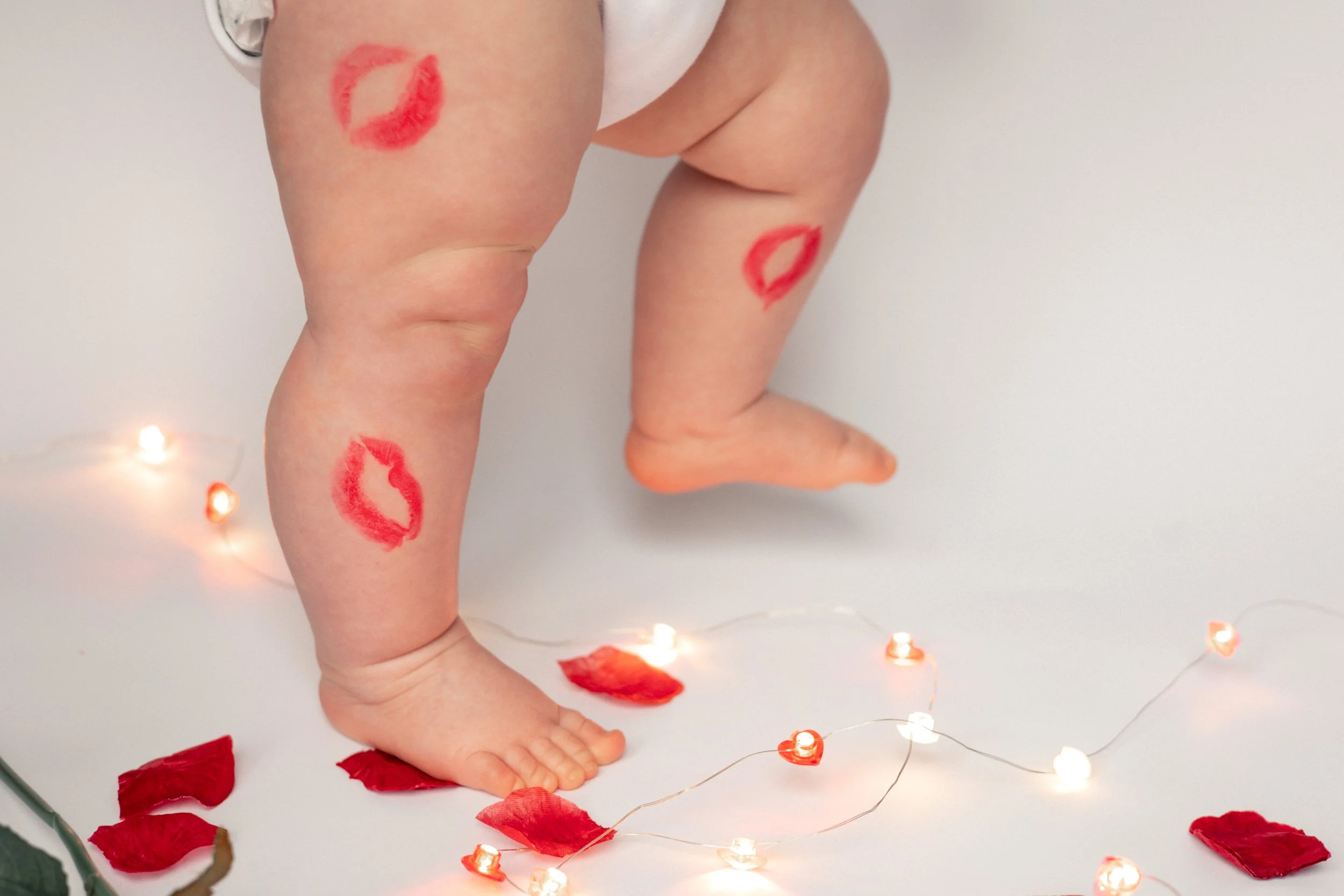 Toddlers legs covered in red lipstick kisses for Valentines Day