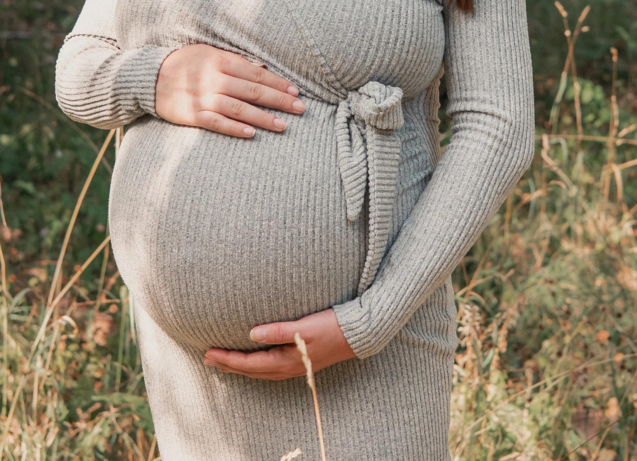 Close up of mum to be embracing bump