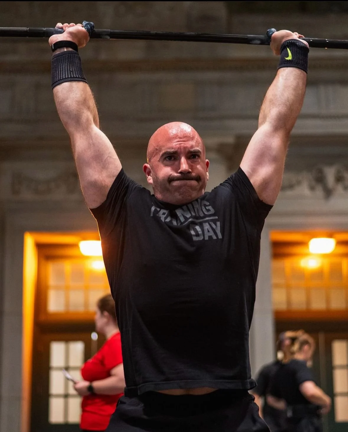 Man lifting a barbell overhead during a workout in a gym.