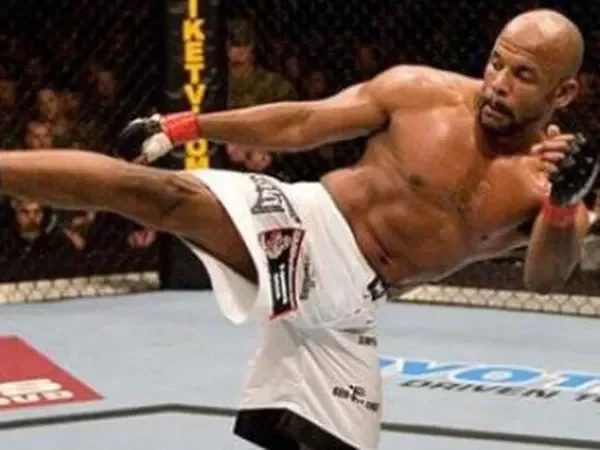 Mixed martial artist executing a high kick inside the octagon during a fight.