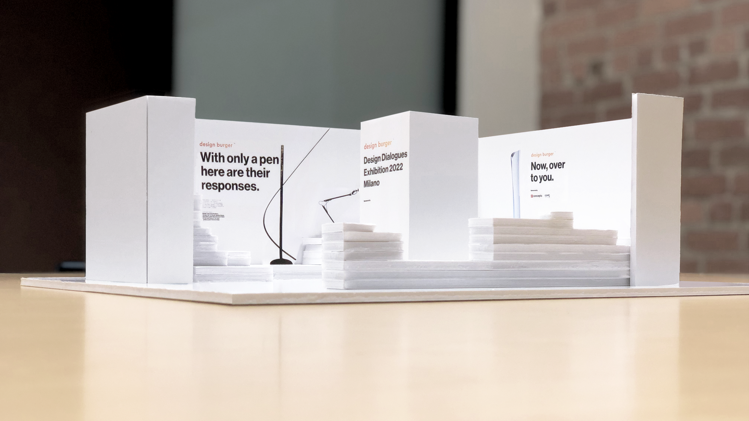 White foam core architectural scale model of the exhibition layout, showing graphics, plinths, and placement of designer products.