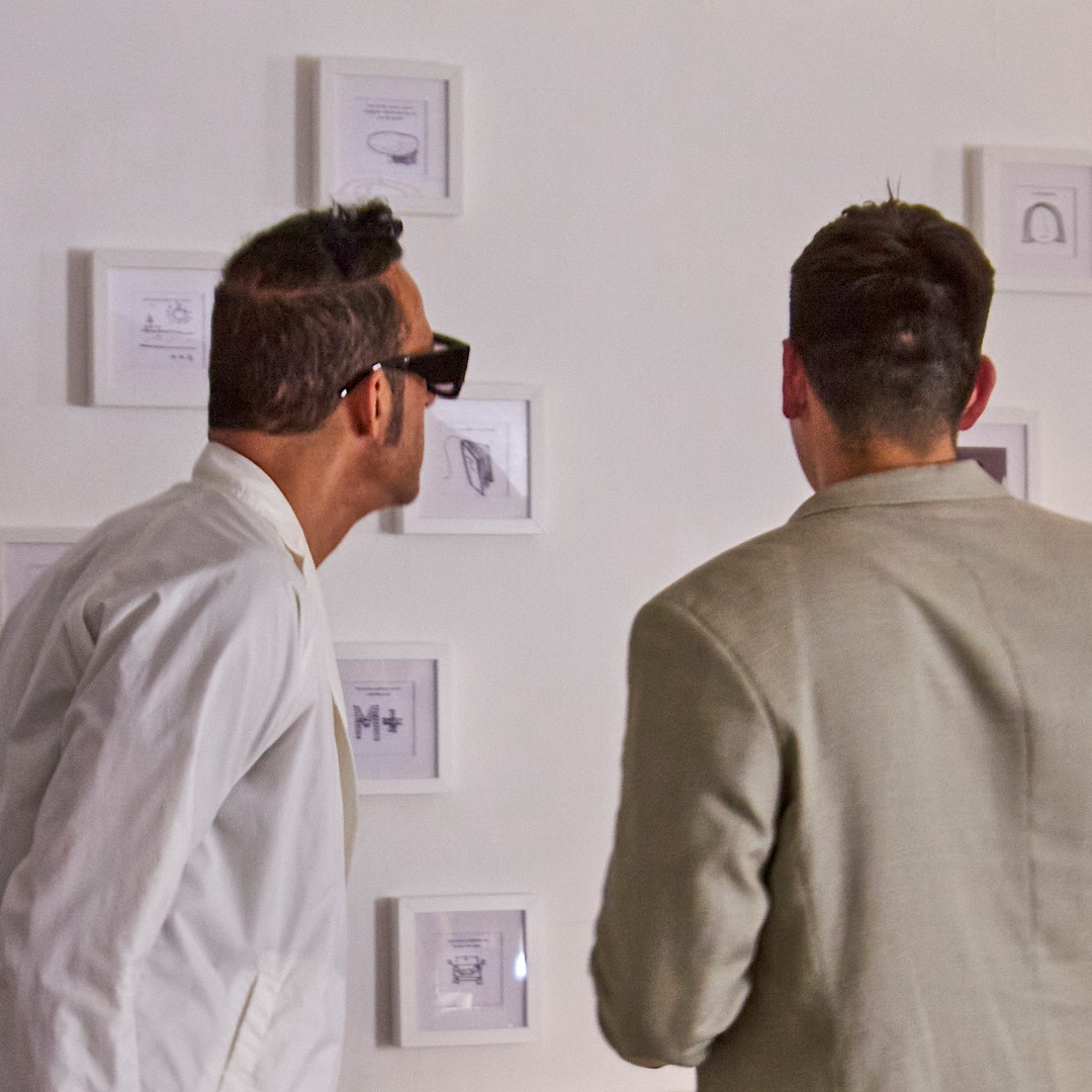 Karim Rashid and Design Burger founder examining visitor sketches on the interactive wall during the exhibition opening.