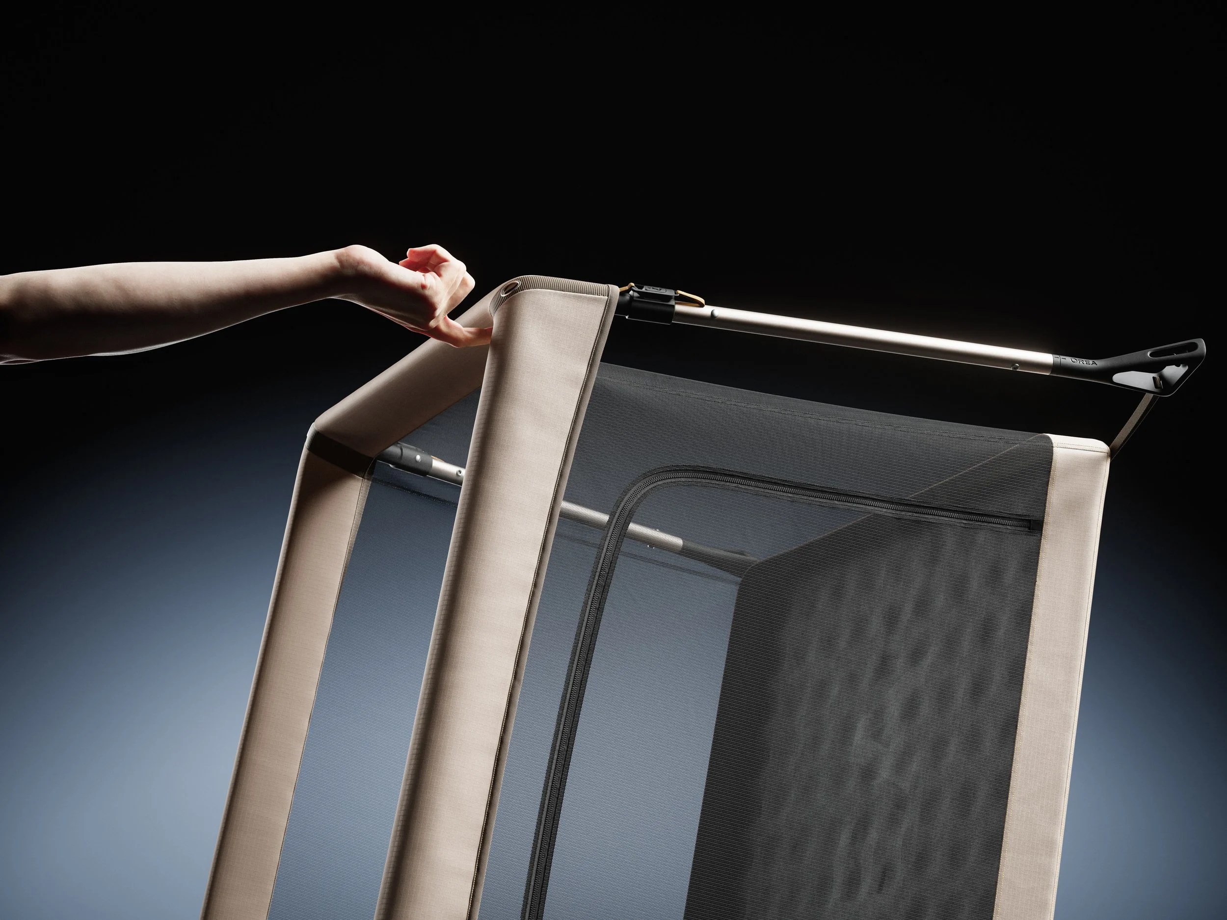 Corner view of the Orea travel crib being held by one finger, showing it lightweight structure.