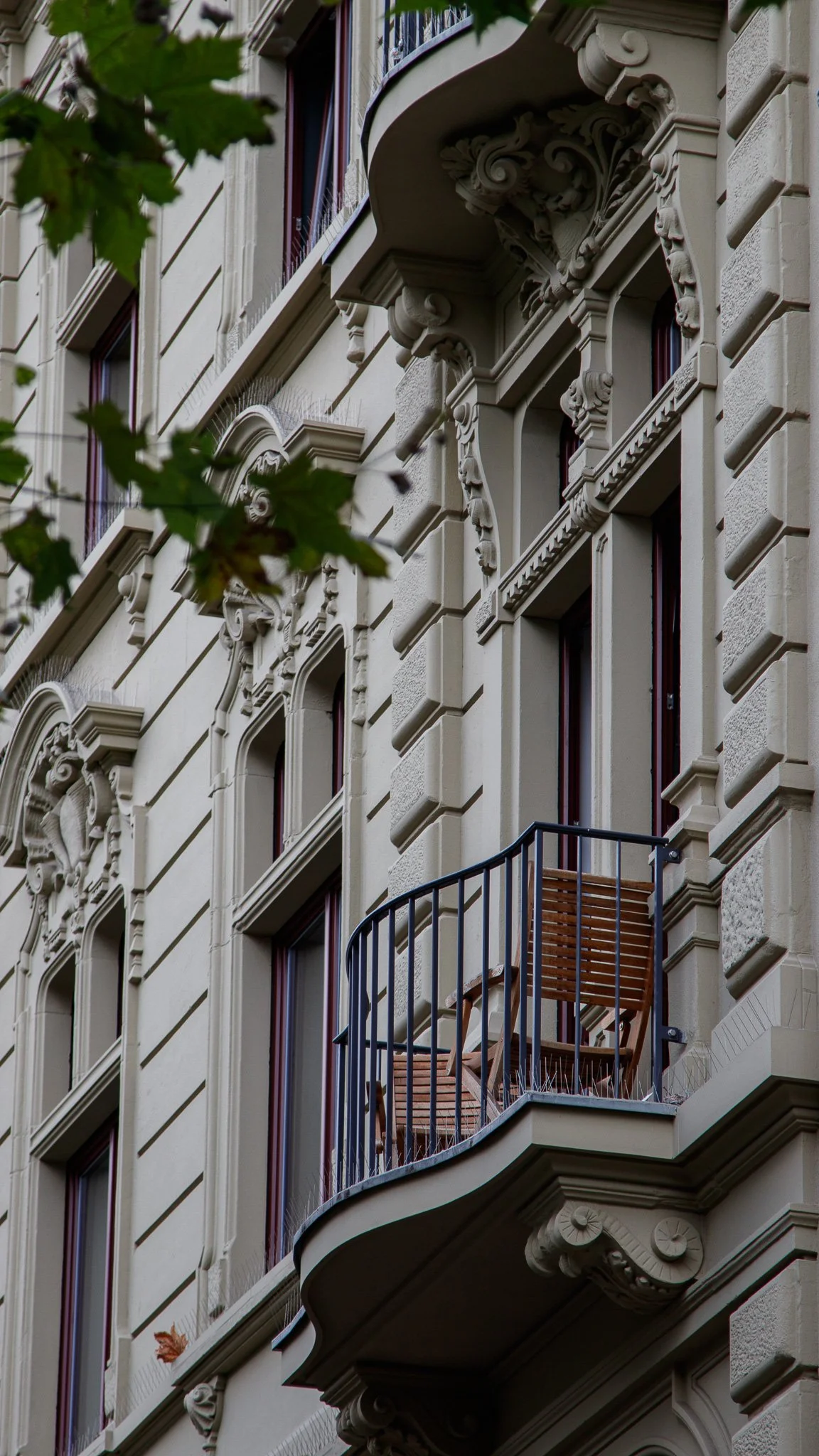 Fassadenseite eines alten Gebäudes mit mehreren Fenstern, Balkonen und kunstvollen architektonischen Details.
