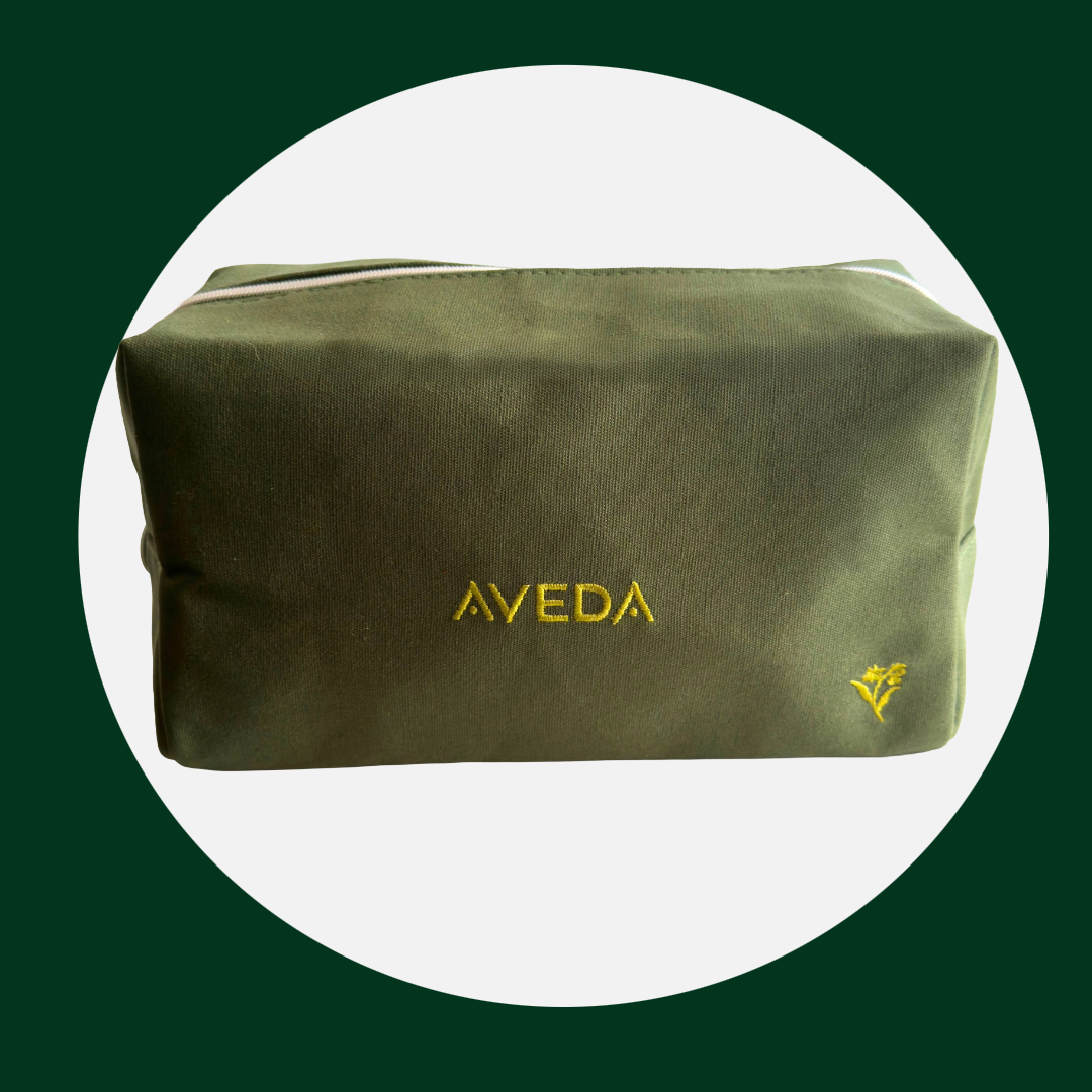 Makeup bag with yellow embroidered "AVEDA" logo and a small yellow floral embroidery.