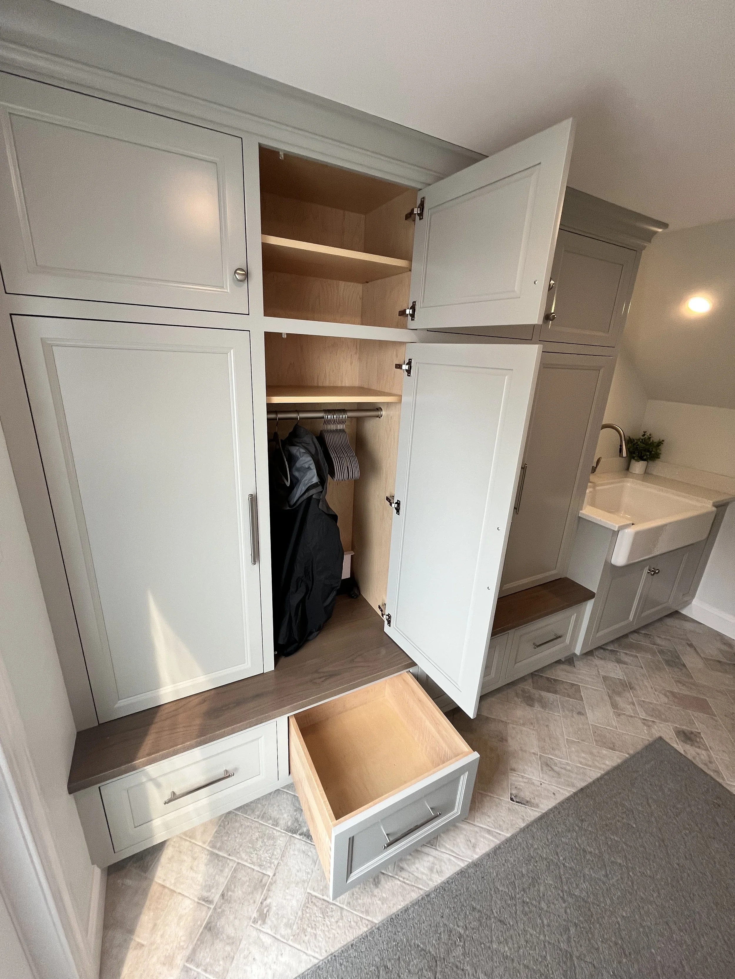 Open kitchen cabinet reveals empty shelves, with additional closed cabinets above and below, next to a sink and countertop.