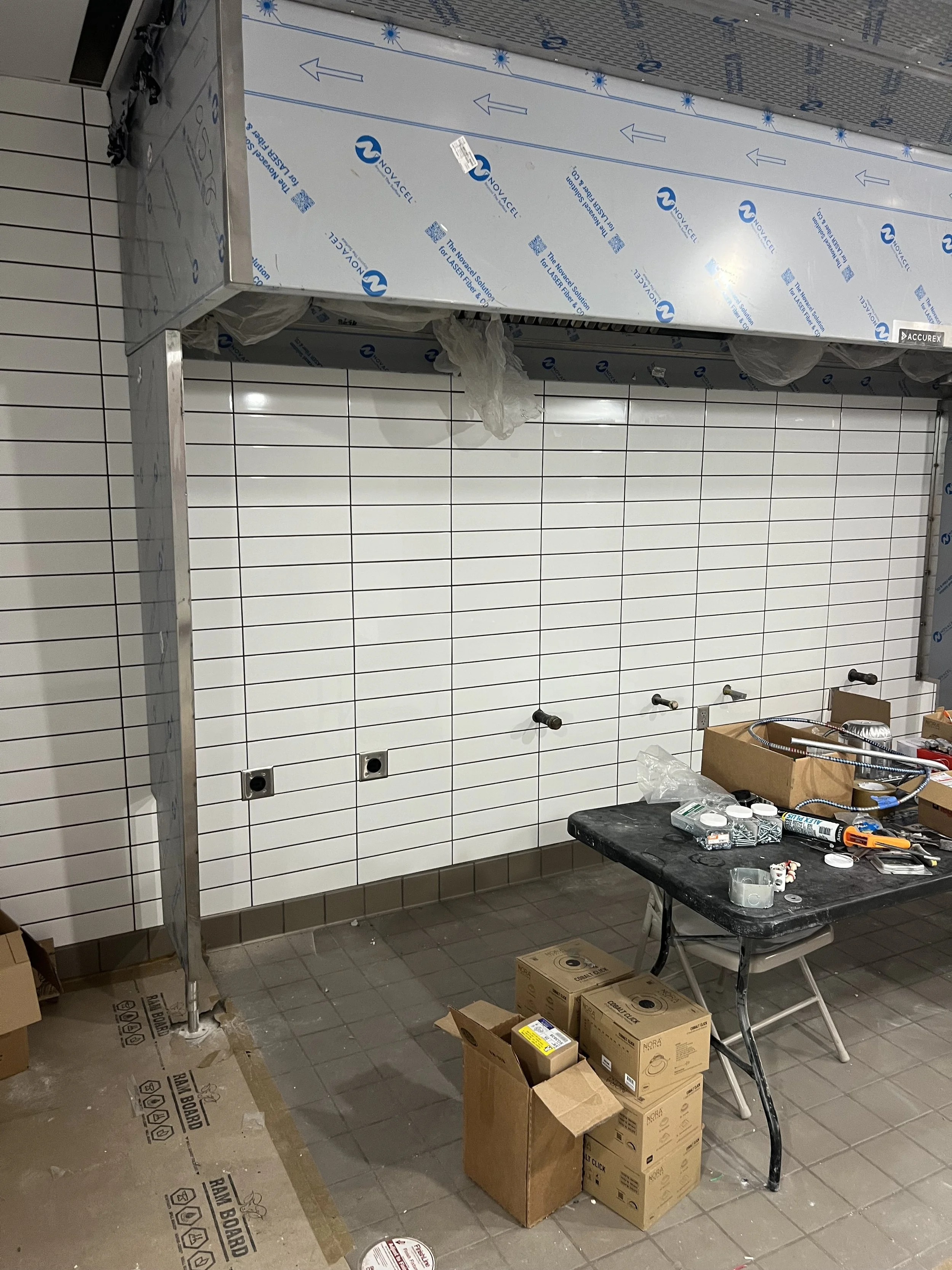Commercial kitchen electrical rough-in with equipment and materials under construction.