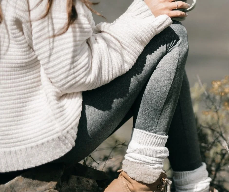 Close-up of a person sitting outdoors in a cozy sweater and knit socks, sunlight casting shadows, therapy in Orinda, CA