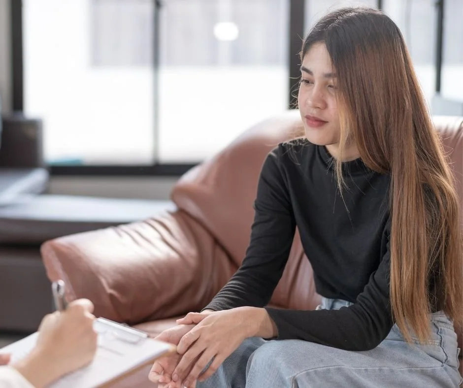 Woman sitting on a couch in a therapy session, talking with a therapist taking notes, representing relationship therapy in Orinda, CA