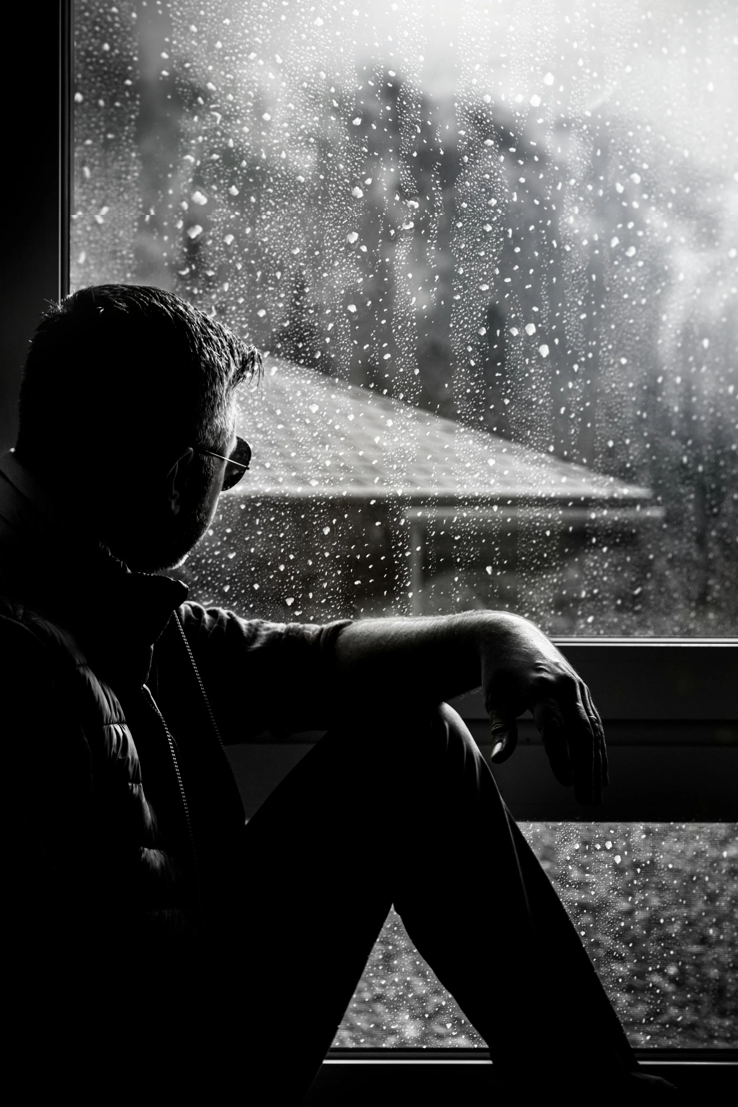 Person looking out a rainy window, representing reflection, solitude, and emotional processing.