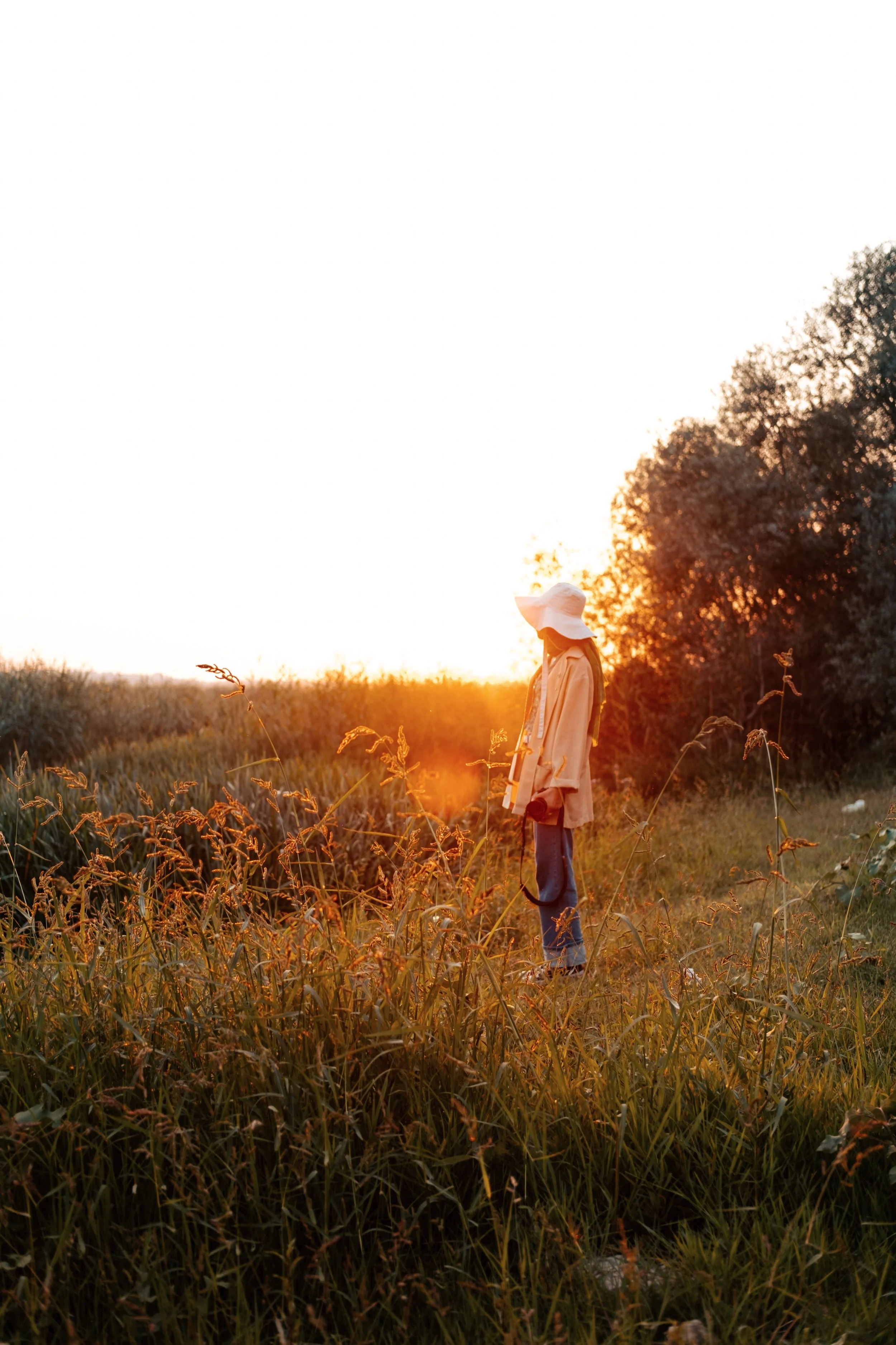 A woman stands in a grassy field at sunset, reflecting during a season of change.
