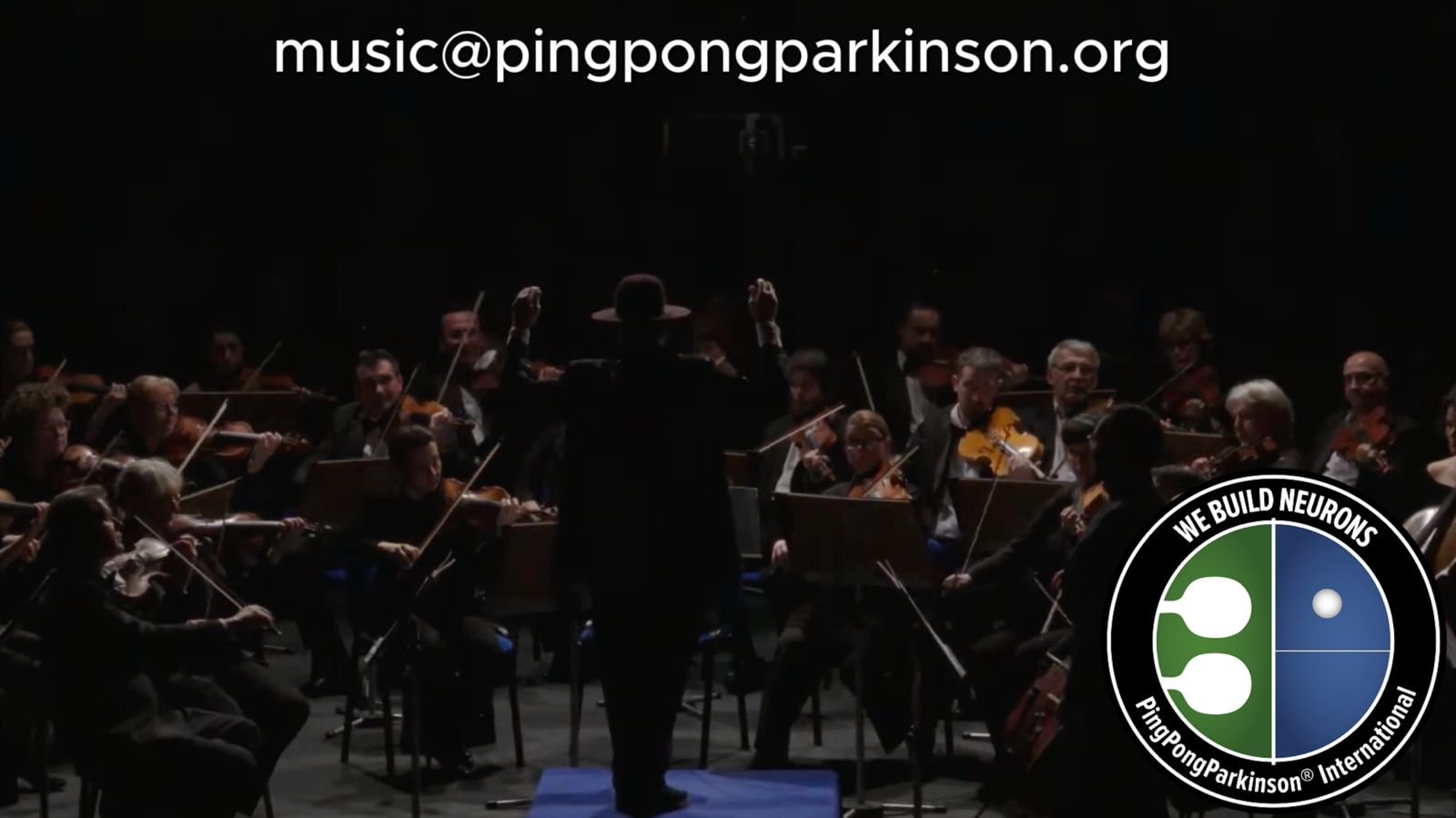 A conductor stands in front of an orchestra, arms raised.