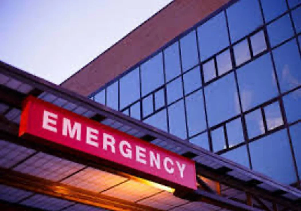 Hospital emergency entrance with a bright pink sign reading 'EMERGENCY' on the building exterior.