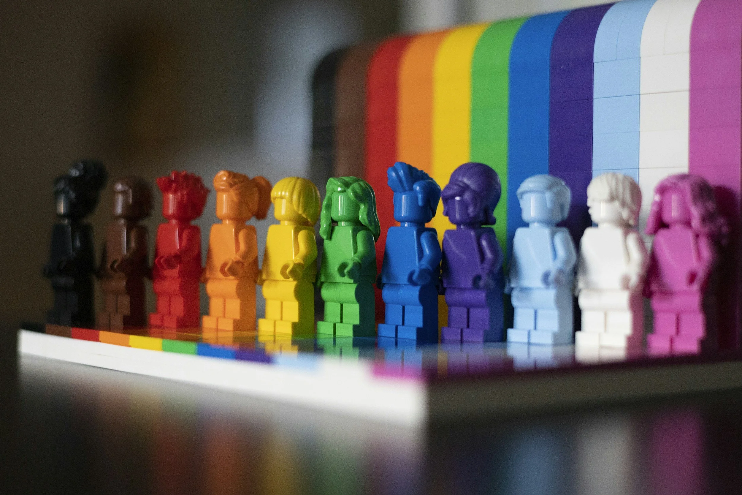 Colorful LEGO figures arranged in Pride flag colors representing diversity, creativity, and community in queer-affirming therapy.